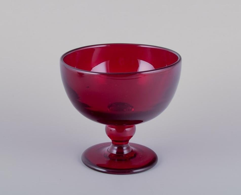 Monica Bratt for Reijmyre, Sweden. Bowl and bowl on foot in wine-red mouth-blown art glass.
1960s/1970s.
Perfect condition.
Centrepiece: H 13.2 cm x D 14.3 cm.
Bowl: H 6.3 cm x D 14.3 cm.

Founded in 1810 in the southern region of Sweden, Reijmyre