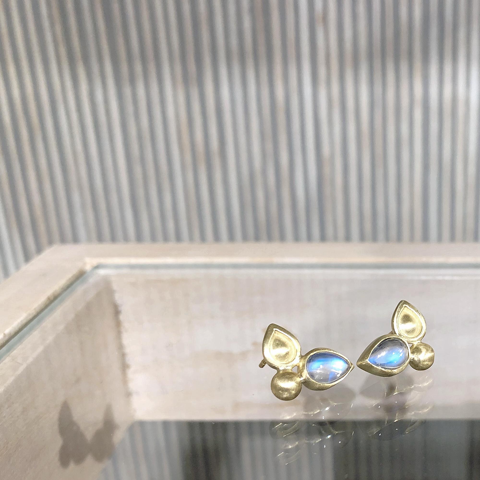 Double Shield Stud Earrings handcrafted by jewelry designer Monica Marcella featuring a matched pair of pear-shaped blue moonstones bezel-set in matte-finished 18k yellow gold with 18k gold posts. 