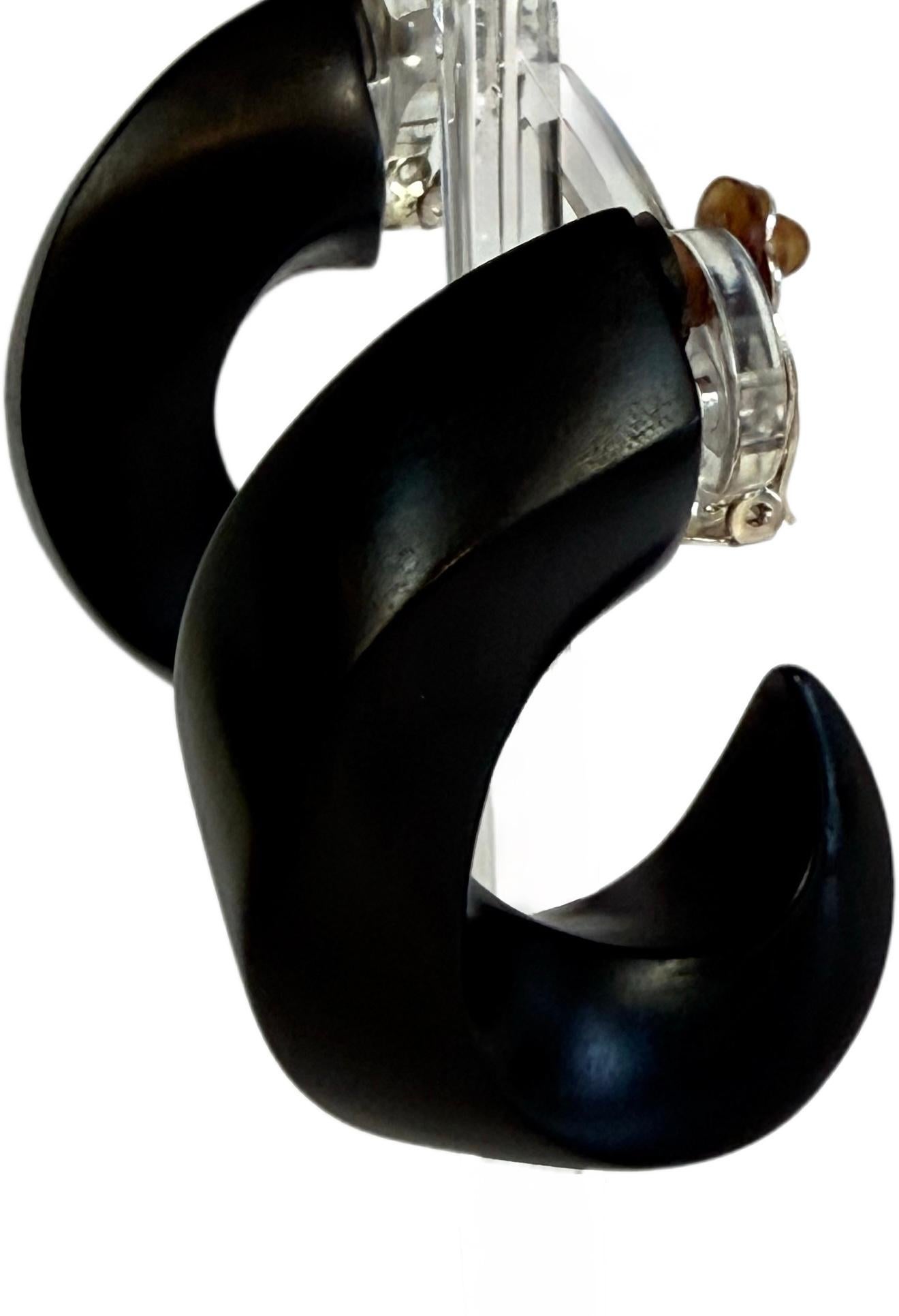 Statement-making and highly collectible, these dramatic vintage 1980s large black wood clip-on earrings by Danish design house Monies embody the bold, sculptural aesthetic that defined the brand’s rise to global cult status. Crafted in a striking