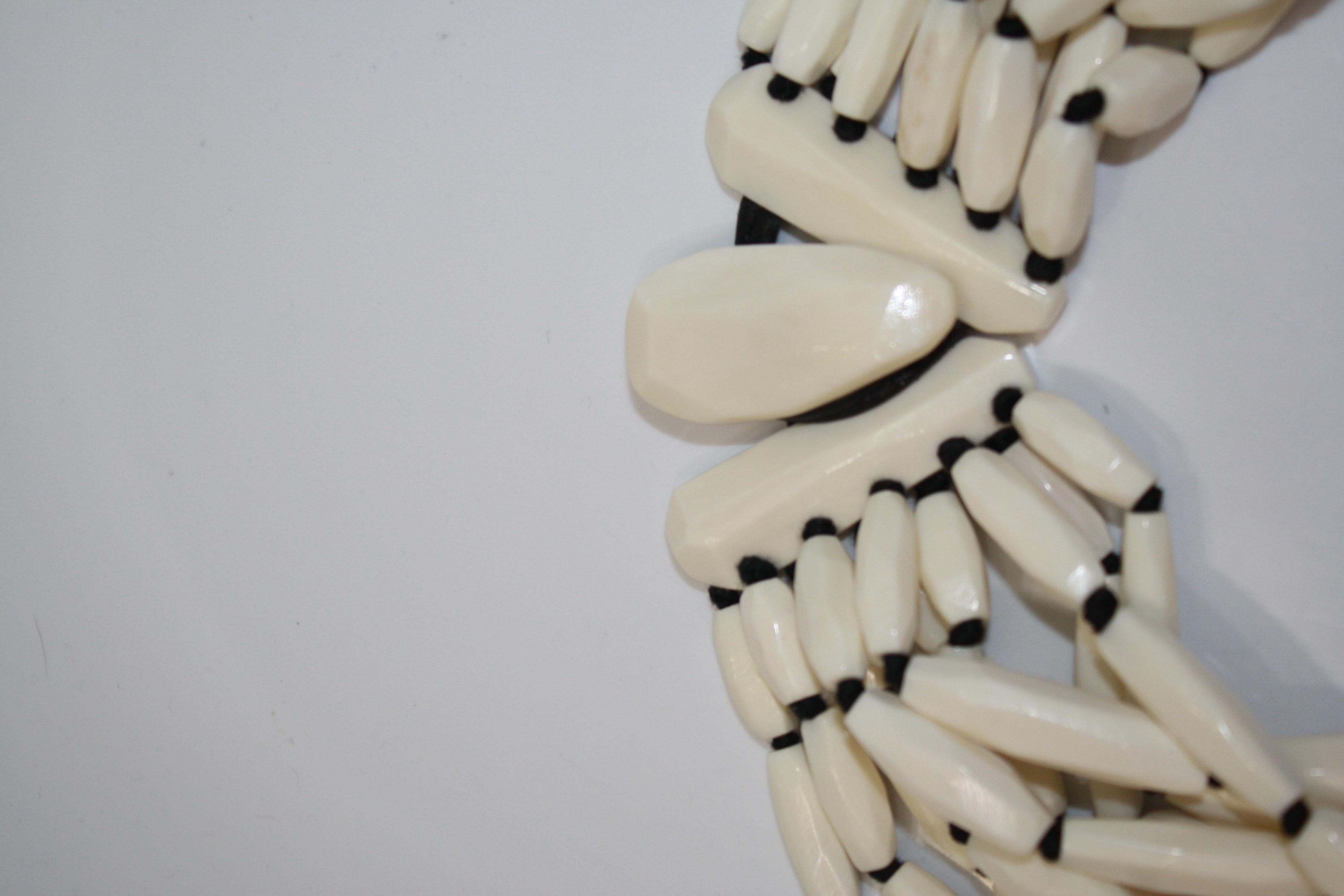 10 strands of oblong bone beads threaded through with a leather strand. Hook and eye clasp.
signature on clasp