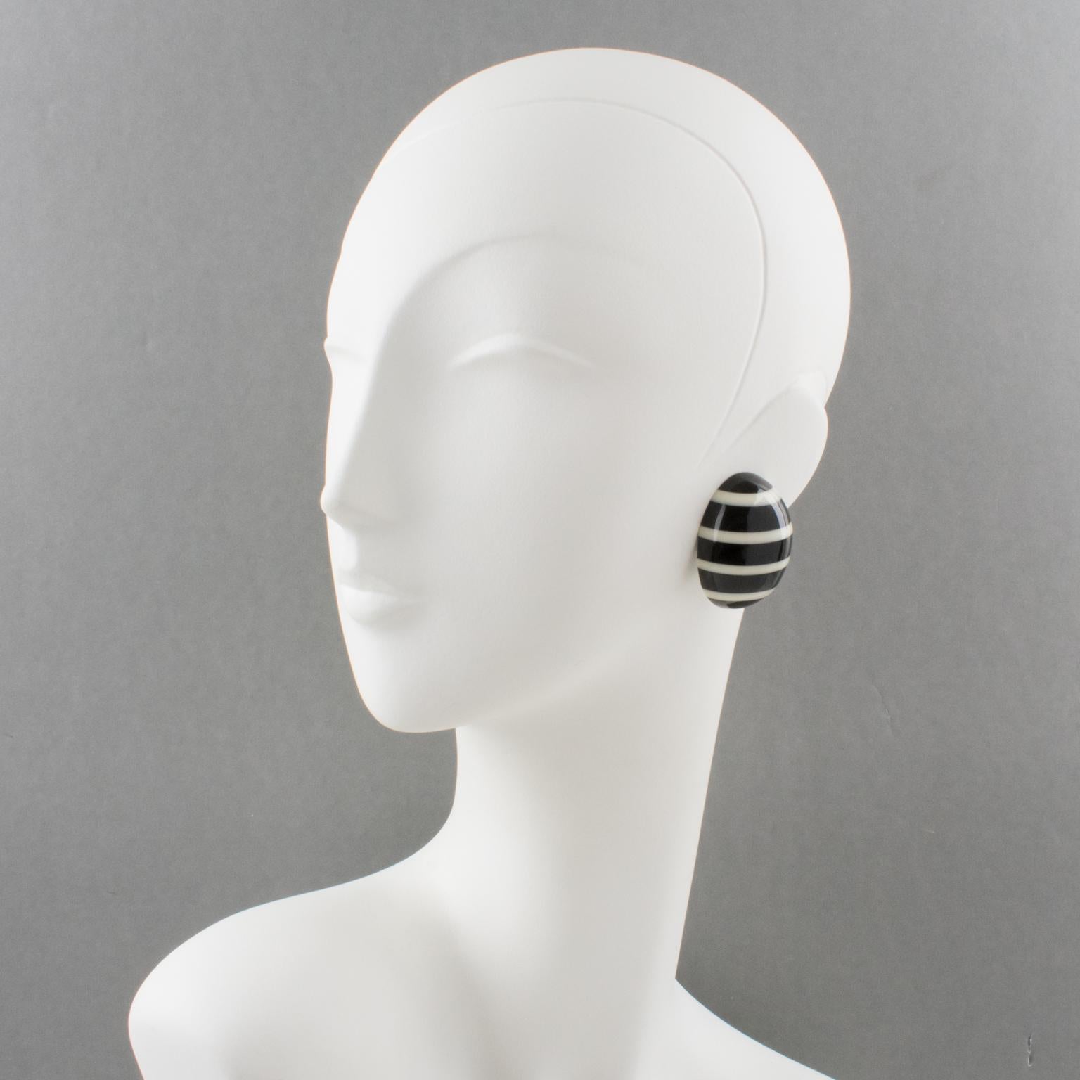Elegant clip-on earrings by Gerda Lyngaard for Monies. These earrings feature a smooth hand-carved ovoid domed shape with a striped design in black and white contrasted resin. Marked 