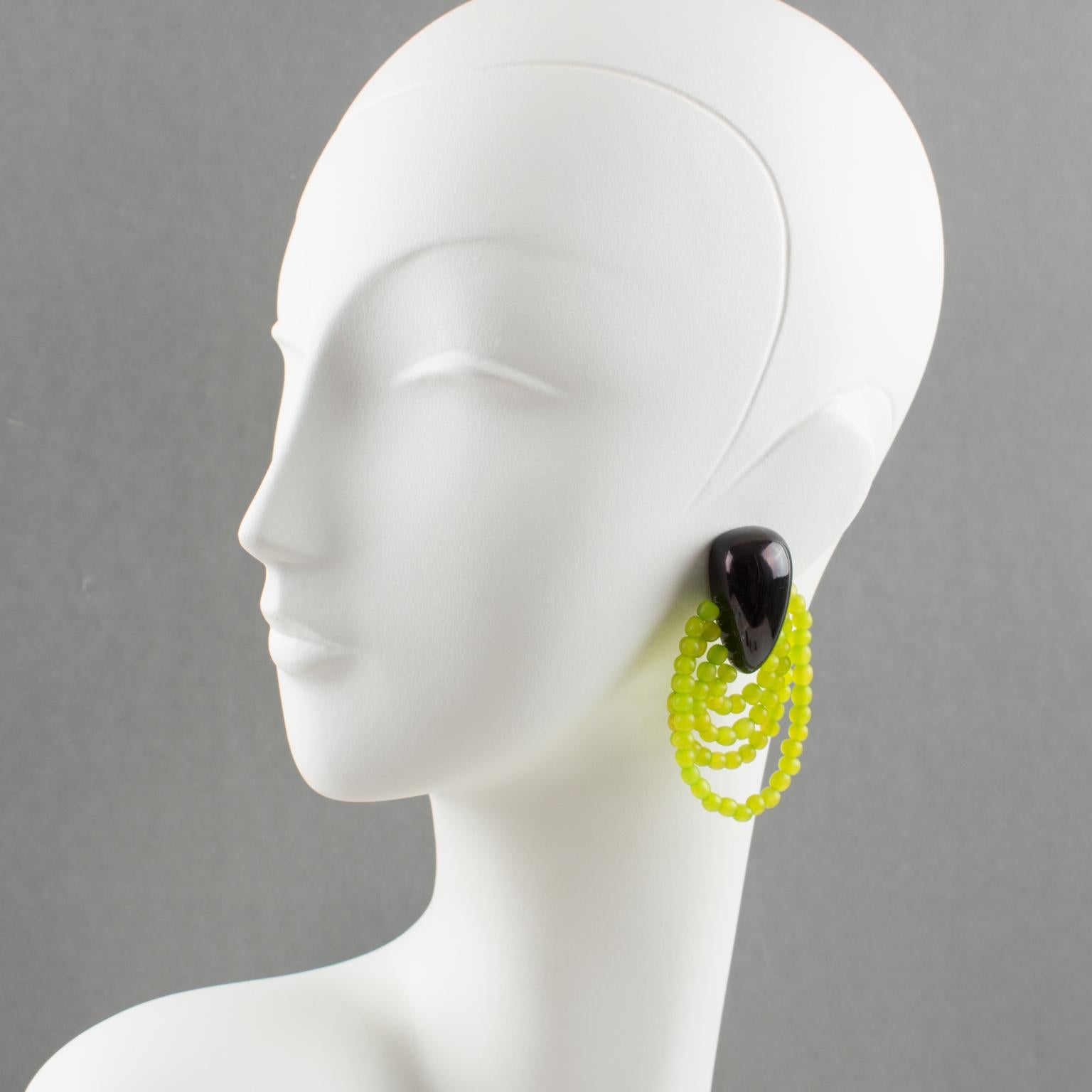 Elegant oversized clip-on earrings by Gerda Lyngaard for Monies. These earrings feature smooth hand-carved resin carved and treated to resemble faux horn material in a modified teardrop shape. They have four graduated loops of frosted green