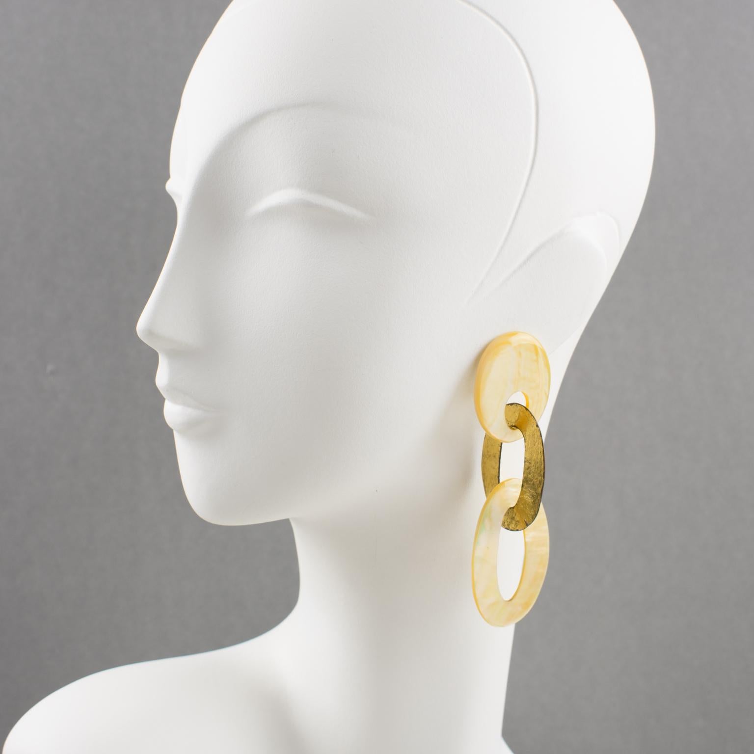 Gorgeous oversized clip-on earrings by Gerda Lyngaard for Monies. Large geometric oval flat link elements in gold foil coated metal contrasted with natural mother of pearl. Marked 'Monies' on each ear clip. 
Measurements: 3.94 in. long (10 cm) x