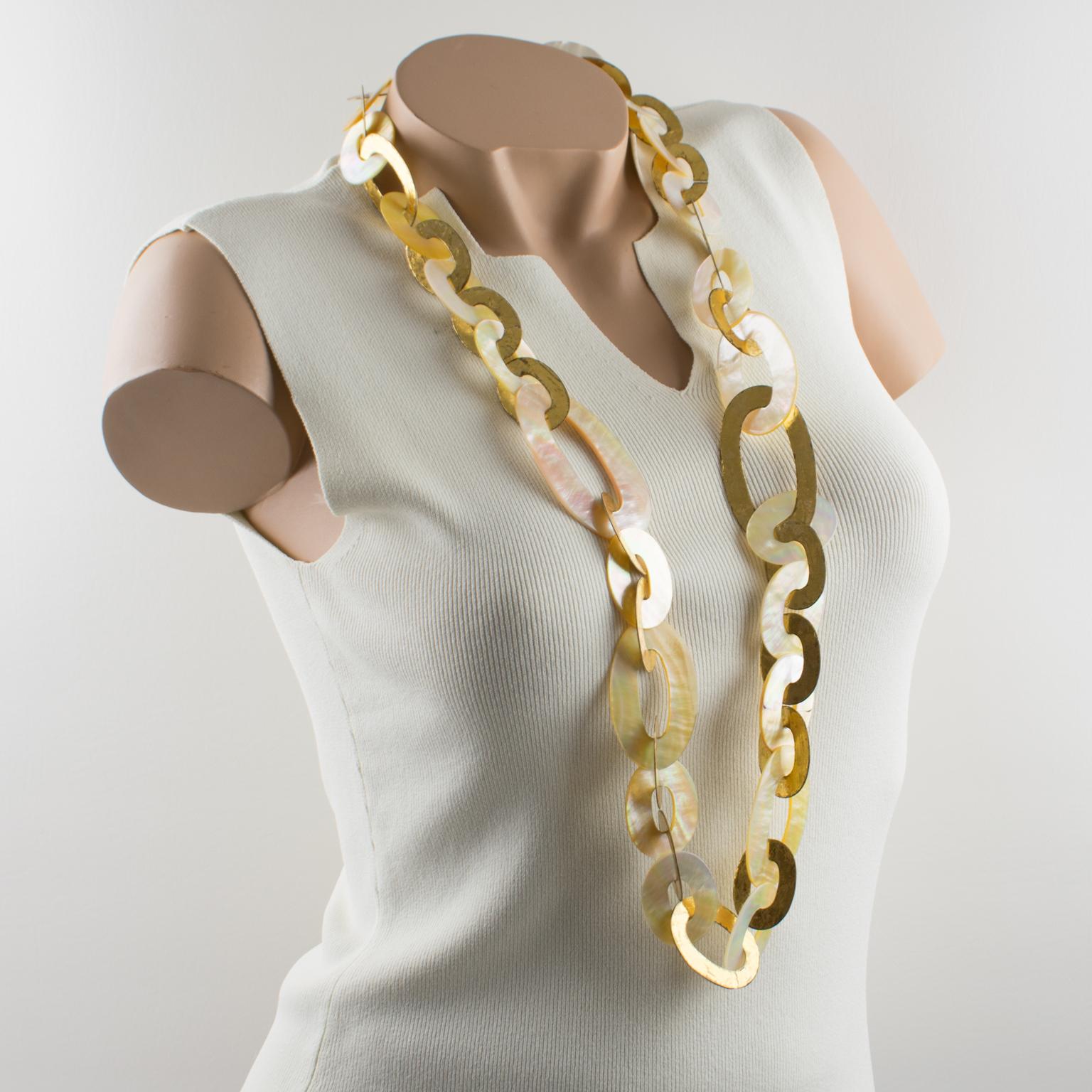 This sophisticated extra-long necklace by Gerda Lyngaard for Monies features a dimensional shape with geometric oval flat link elements in gold foil-coated metal contrasted with natural seashell link elements forming an elegant long-worked chain.