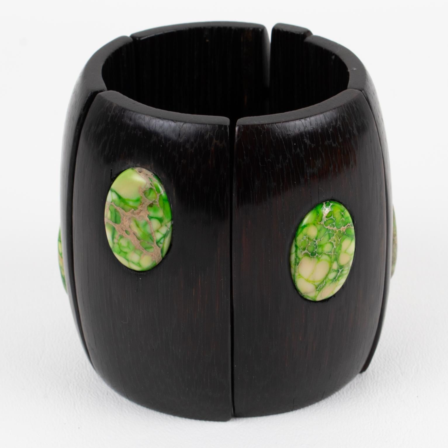 Gerda Lyngaard for Monies designed this gorgeous oversized ebony wood stretch bracelet. The chunky hand-crafted stretch bangle shape is in Ebony wood with polished green moss stone cabochons. This stunning piece with an organic and ethnic flair that