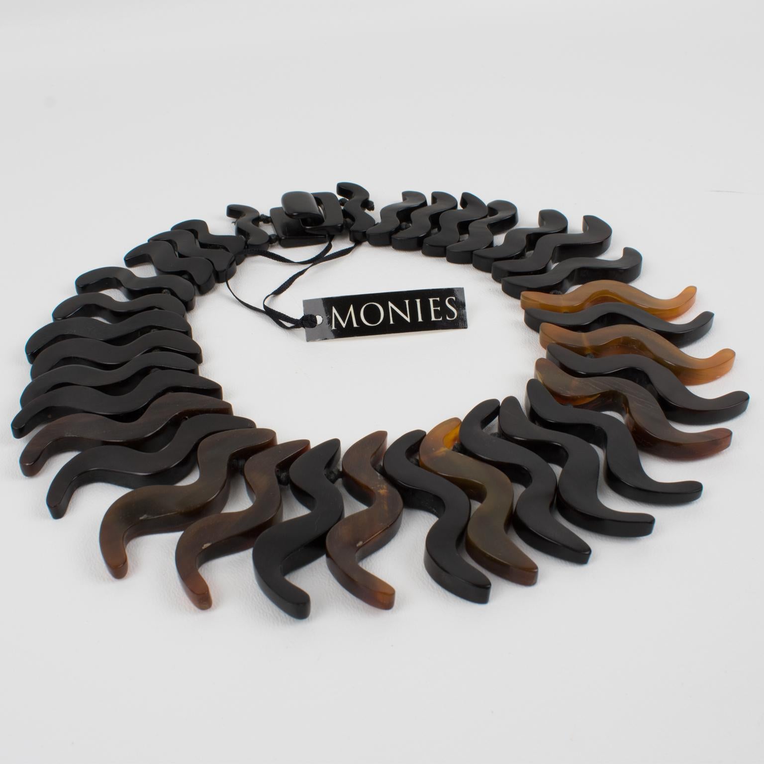 This gorgeous oversized resin necklace by Gerda Lyngaard for Monies features chunky hand-crafted zig-zag-shaped resin elements with carving and is treated to resemble faux-horn material. The choker has a black resin closure clasp. The organic and