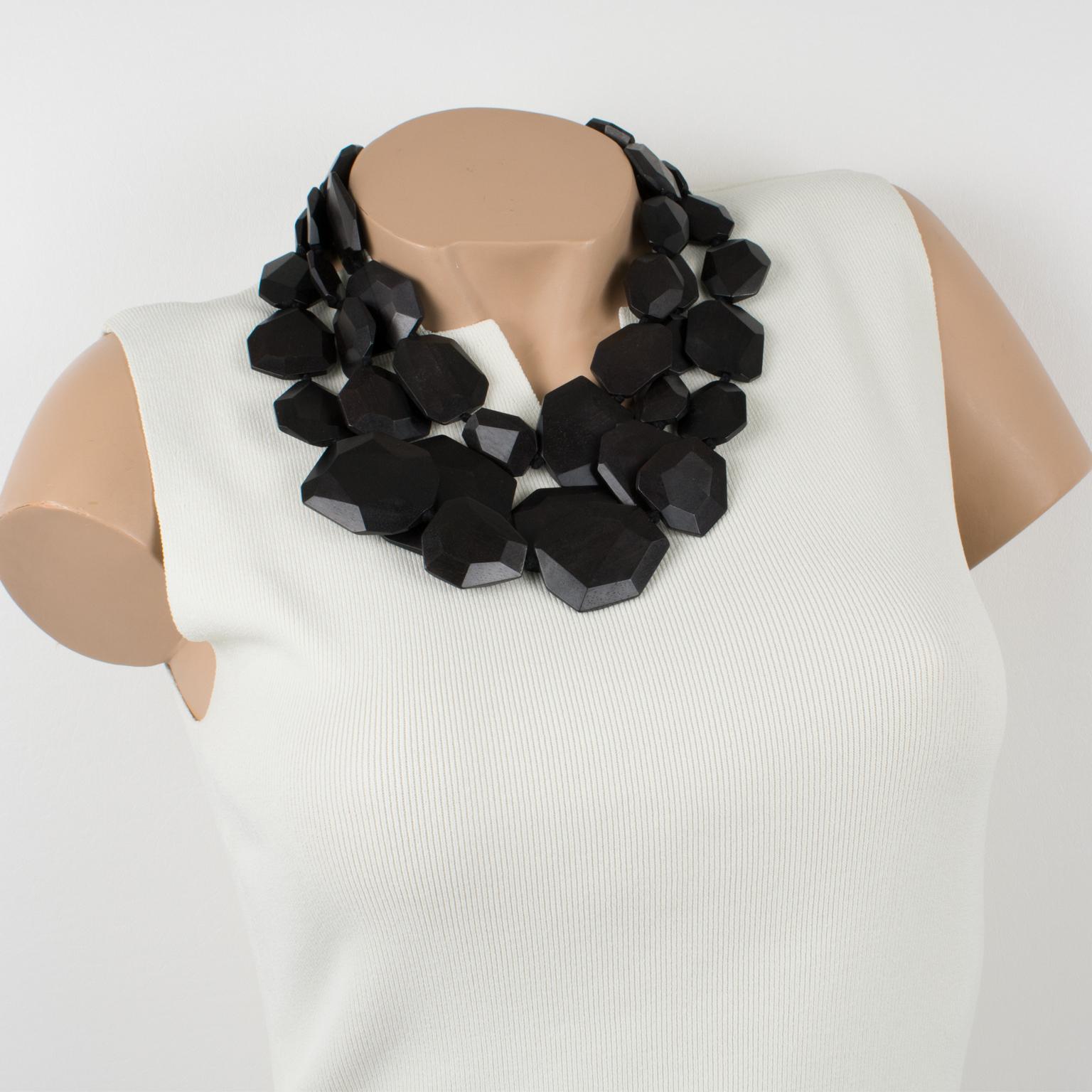 Spectacular oversized wood necklace by Gerda Lyngaard for Monies. Chunky hand-crafted three strands of carved pebbles shaped beads in black Ebony wood. Black leather closure clasp. A real stunning piece by one of the best contemporary fashion
