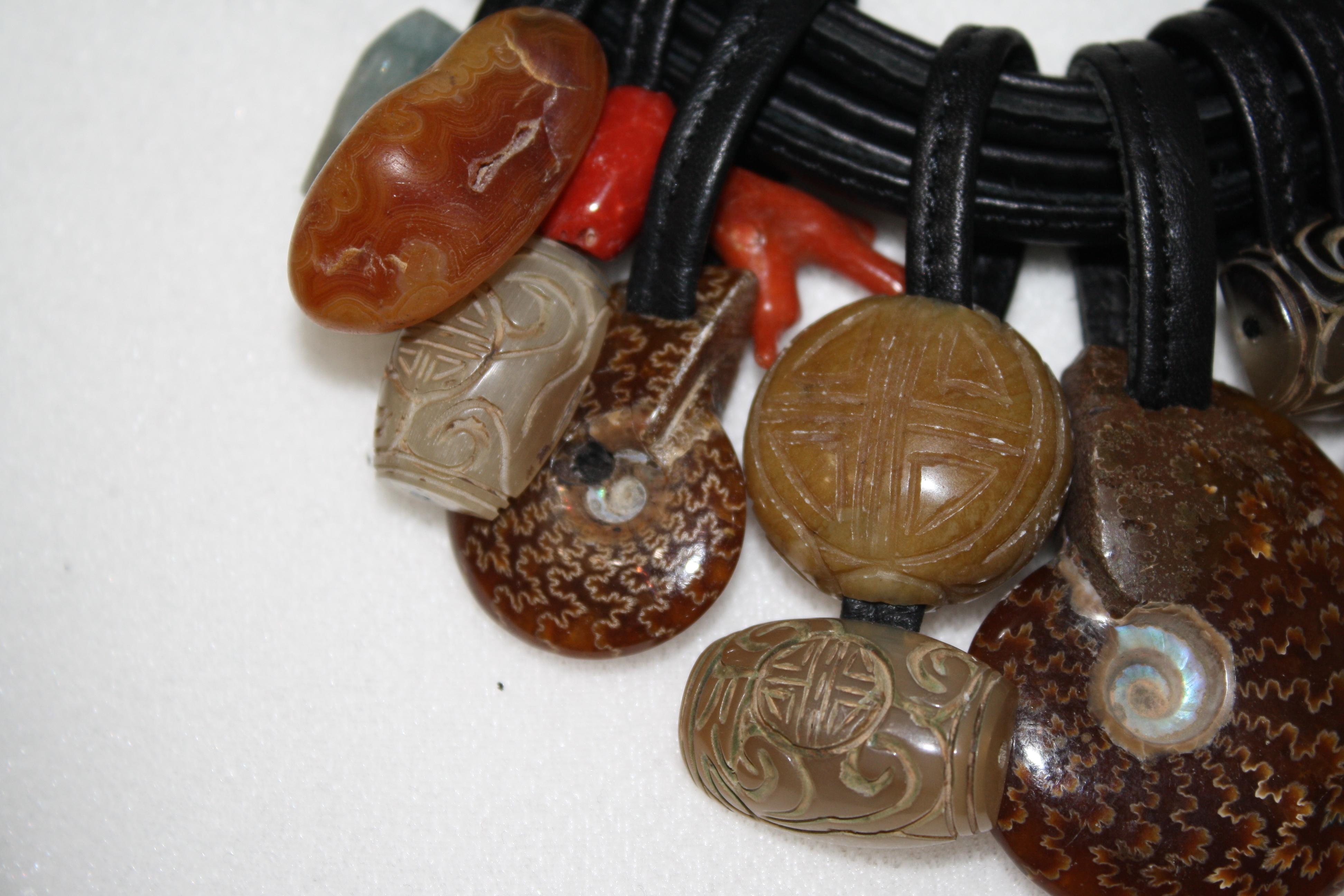 One of a kind semi precious stone threaded on leather can slide around for different looks. Toggle clasp with ammonite stone. Intricate etching and carving on the stones. 8 strands of stitched leather.
Signature on the clasp
A true statement piece
