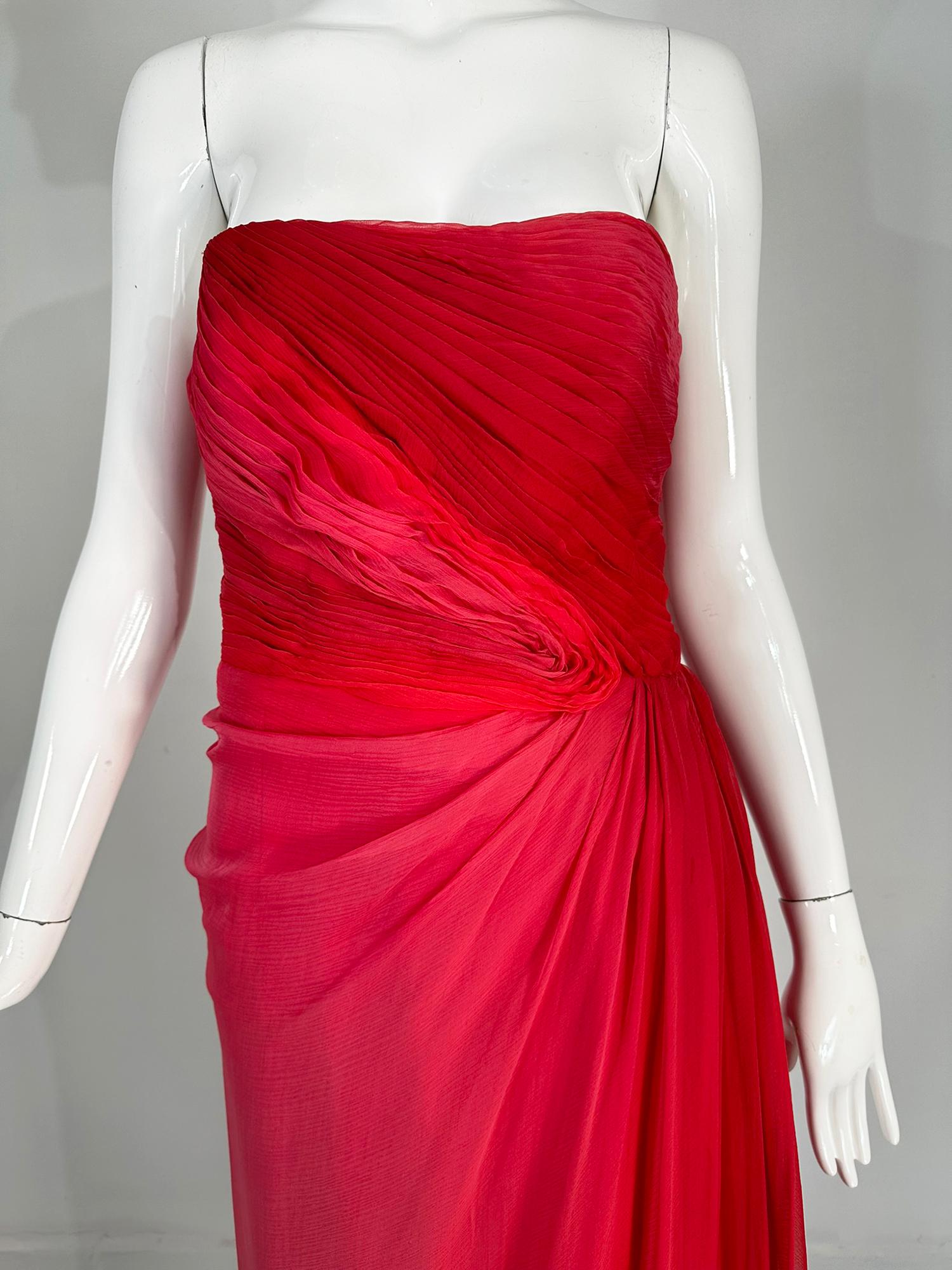 Monique Lhuillier Collection red & pink ombre pleated silk chiffon draped strapless gown. A gorgeous gown, perfect for any big event.
Strapless the bodice is done in ombre dyed pink to red silk chiffon. Diagonally pleated bodice drapes to the left