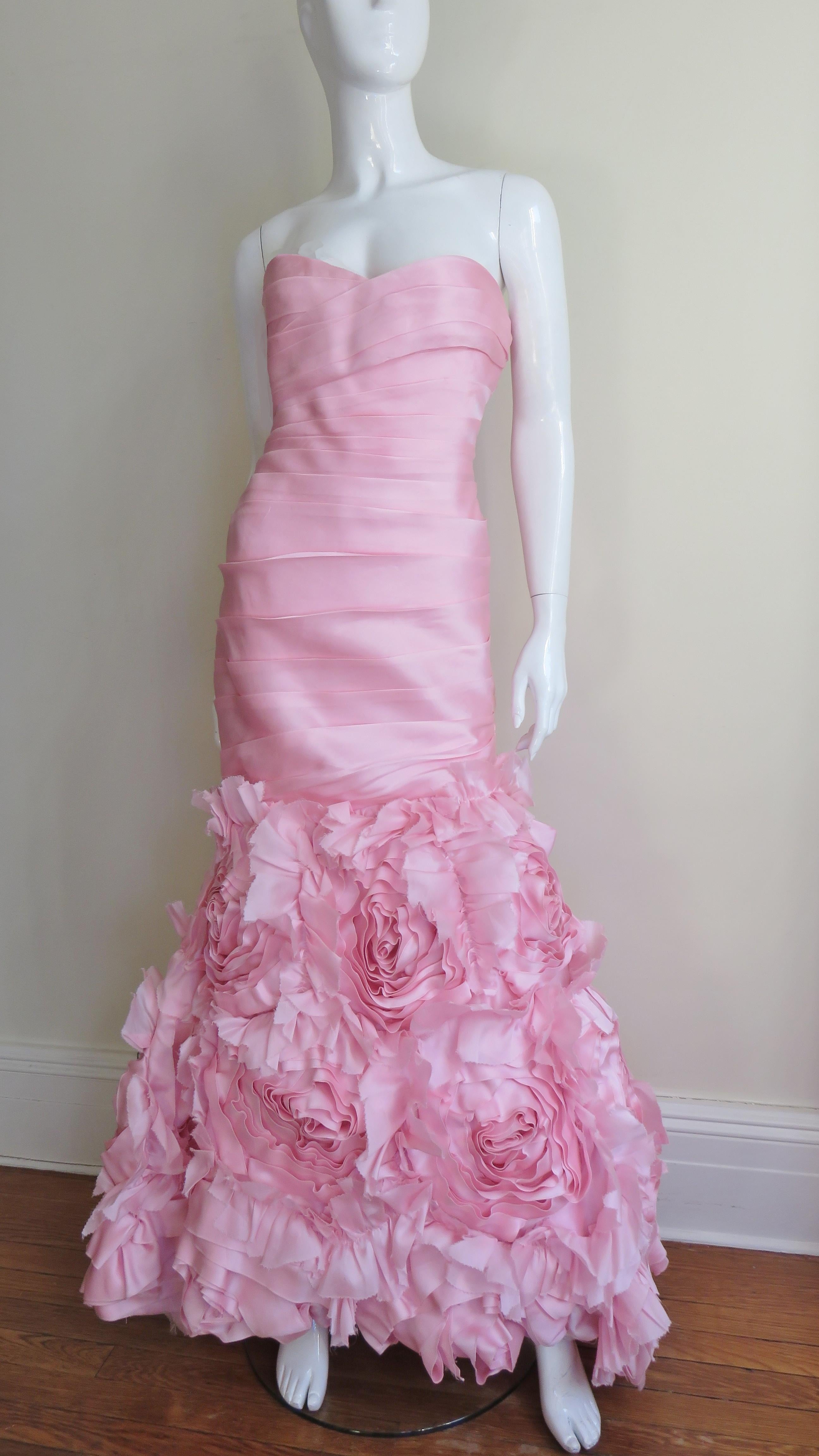 A stunning pink silk strapless gown from Monique L'huillier. Horizontal folds across the body of the dress front and back through to the thighs then at knee level it flares to the hem and is covered with incredible, detailed applique roses in the