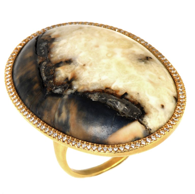 From the sustainable, one-of-a-kind Designer Monique Péan, who sources her materials from unique places and resources.

This exquisite piece presents a center gemstone from ombré-colored polished cabochon oval-shaped, genuine Fossilized Dinosaur