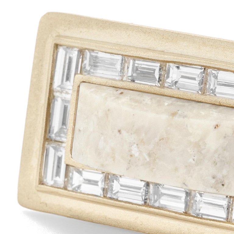 Cream fossilized dinosaur bone and white diamond baguette rectangular ring, 18 carat recycled white gold, 0.64 TCW

The cream hues of this specimen of fossilized dinosaur bone are accented by  white diamond baguettes that trace the angled form and