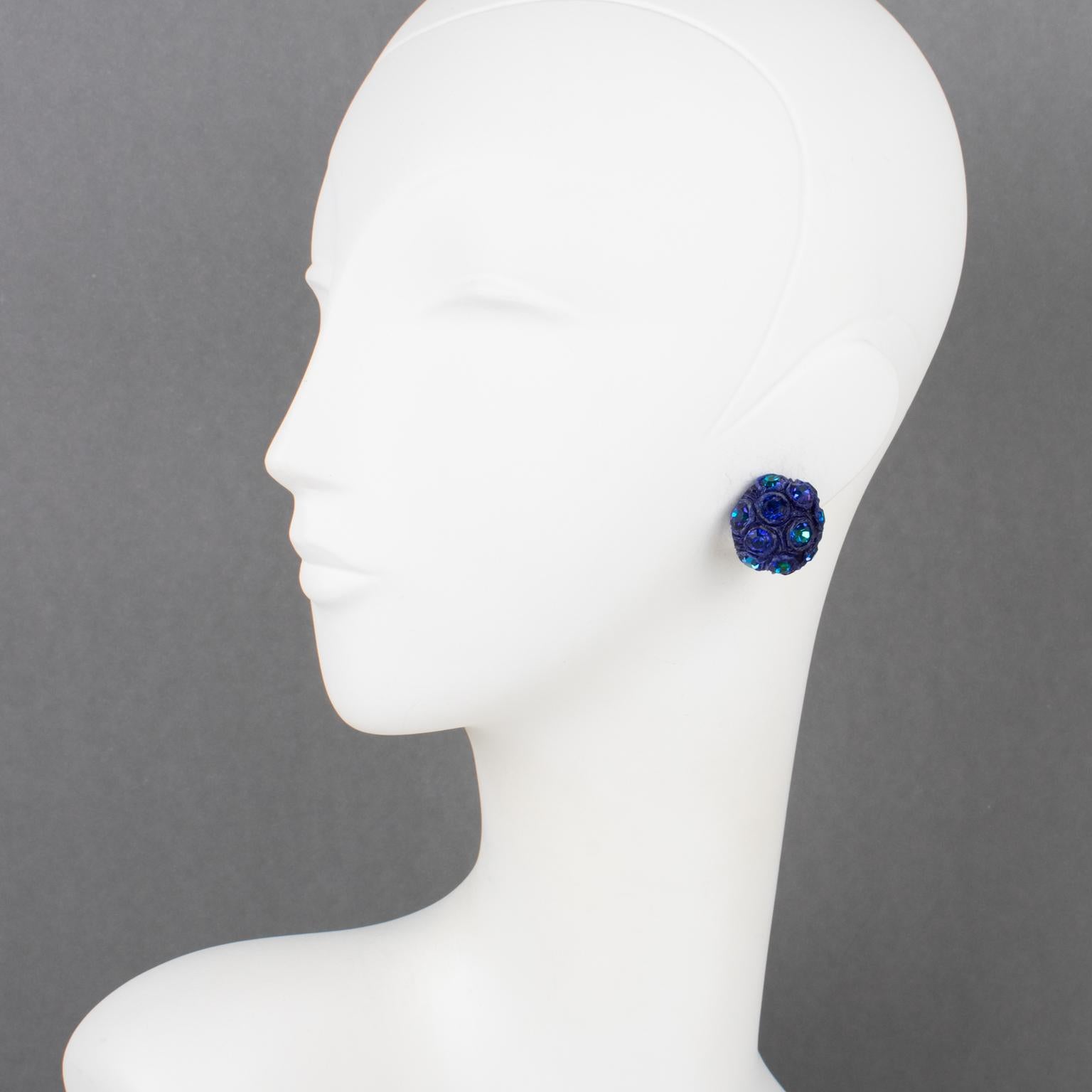 These lovely Monique Vedie resin clip-on earrings feature a delicate rounded domed shape with cobalt blue carved Talosel framing, ornate with faceted crystal rhinestones in AB blue iridescent color. The earrings have the typical French clip-back