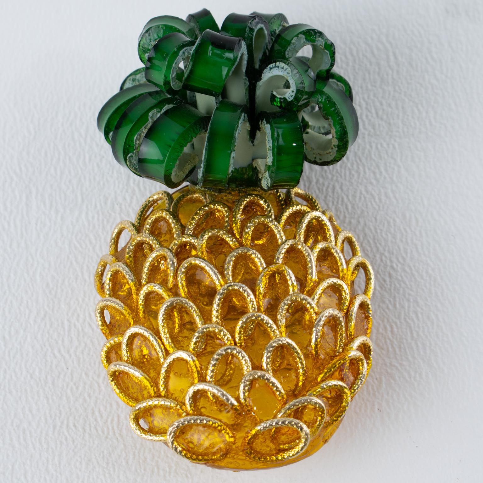 This stunning Monique Vedié Talosel resin brooch features a dimensional pineapple shape in yellow and green colors, adorned with a textured pattern and gilded metal rings that mimic the pineapple's texture. The brooch has its original security