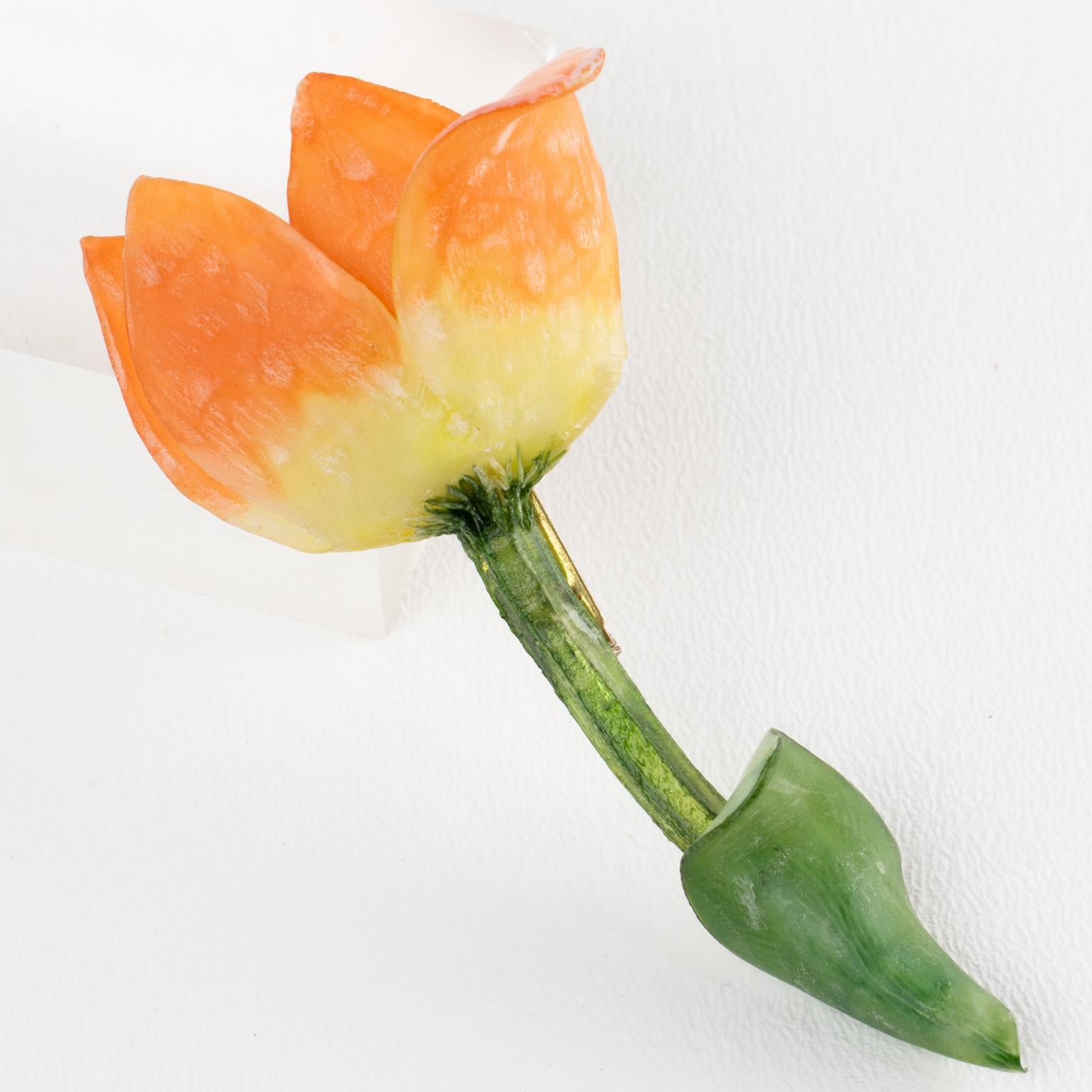 Este magnífico broche de resina o Talosel de Monique Vedie presenta una rara flor estilizada de tulipán dimensional en colores salmón anaranjado texturizado, amarillo claro y verde. La pieza tiene un cierre de seguridad en la parte posterior. No hay