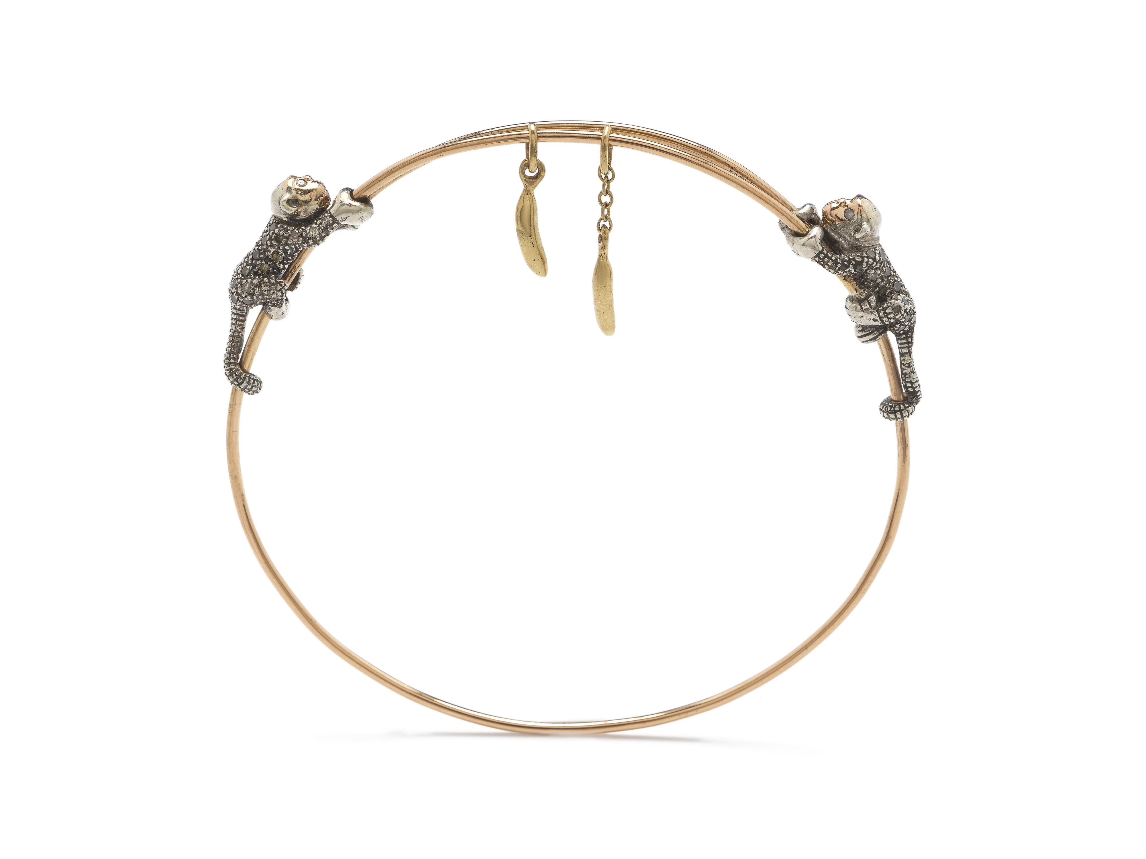 Designed in 18k rose and yellow gold, this fine bangle is set with two 18k rose gold and sterling silver monkeys embellished with brown diamonds, who chase two gold bananas hanging between them. This bracelet’s fitting on the wrist can be adjusted,