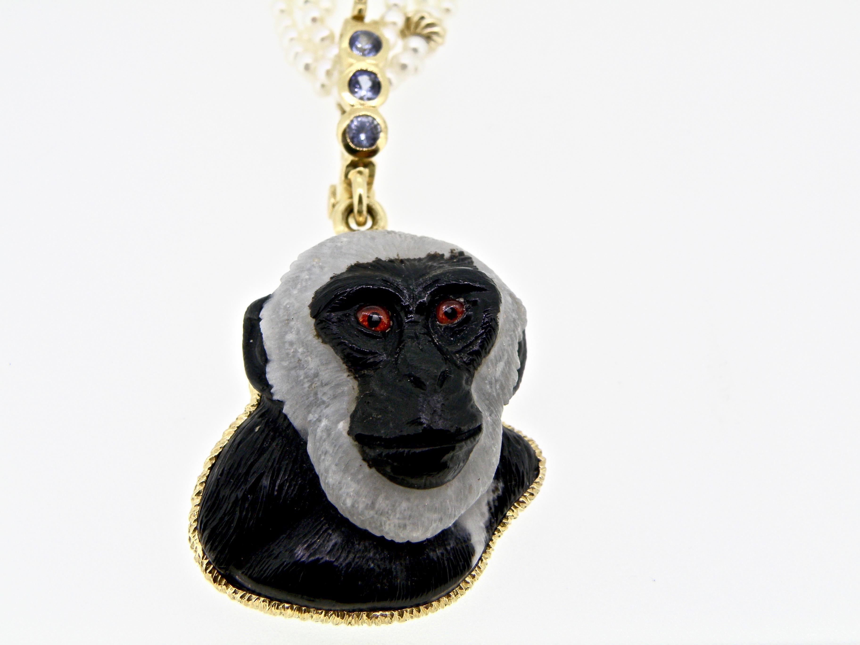 27 x 32 mm hand-carved obsidian with grey mane primate with inlay painted citrine eyes hung by 18K gold bezel and sapphire bail.