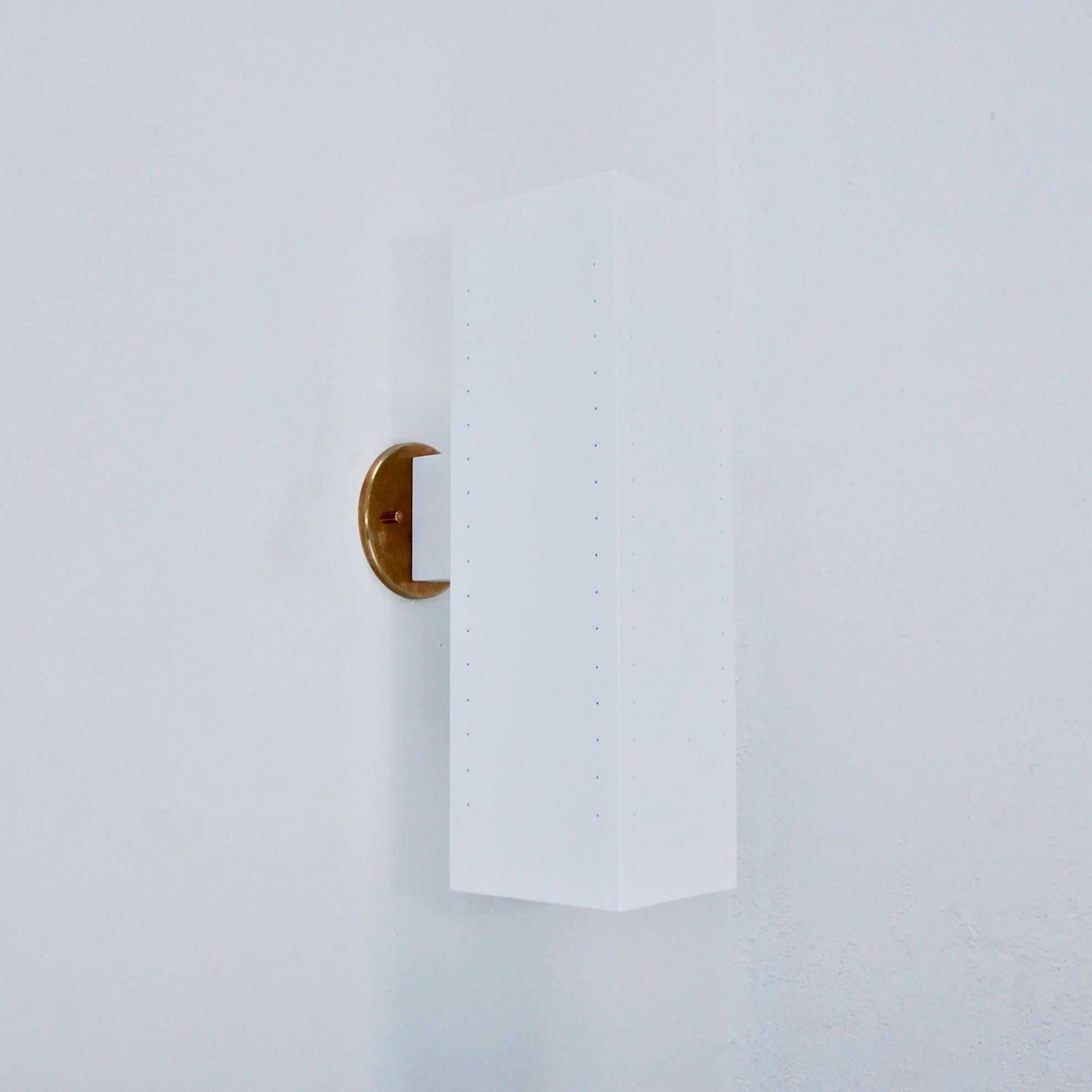 Faisant partie de la collection contemporaine de Lumfardo Luminaire, l'applique d'extérieur MonLUlith est une grande applique rectangulaire perforée en aluminium blanc peint et plaques arrière en laiton patiné. Chaque applique est équipée de 2