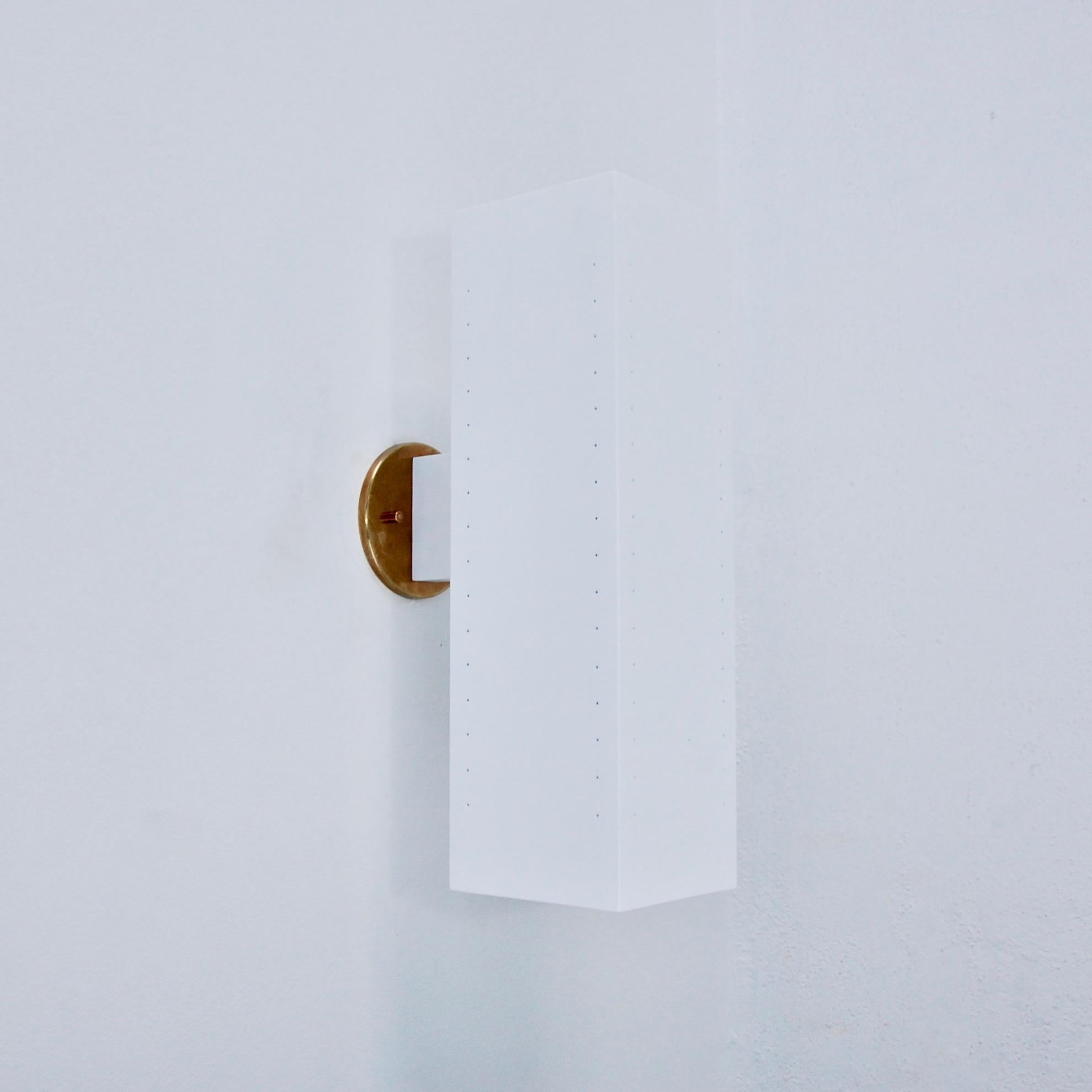 Die MonLUlith Außenleuchte aus der zeitgenössischen Collection'S von Lumfardo Luminaires ist eine große, rechteckige, perforierte Leuchte aus weiß lackiertem Aluminium und patinierten Messingplatten. Bestückt mit (2) E26-Fassungen mit mittlerem