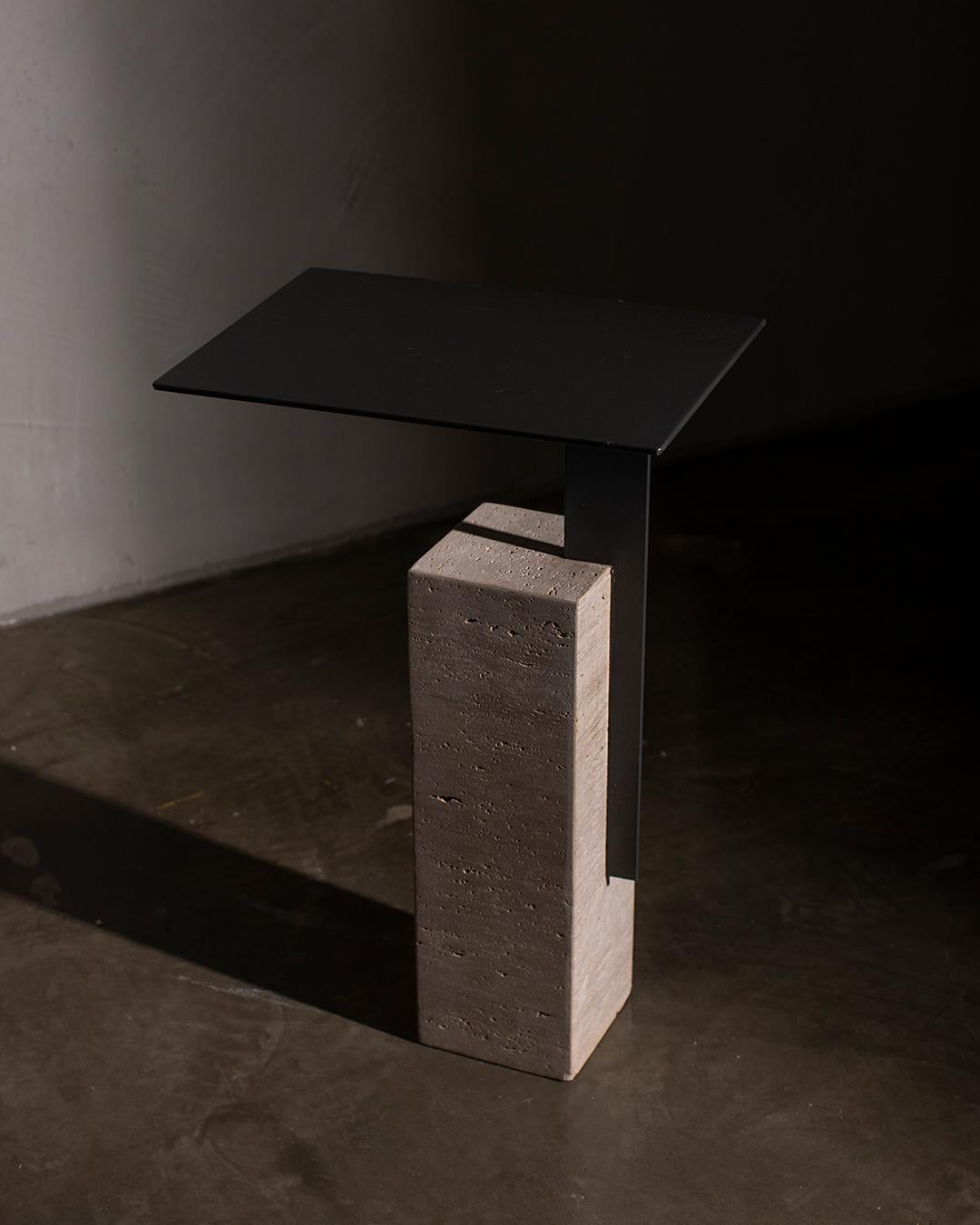 La table d'appoint Mono est dotée d'un fin plateau rectangulaire qui repose élégamment sur un épais piédestal en pierre, donnant l'impression de flotter dans les airs. La silhouette élancée de la table, ses proportions élégantes et sa texture