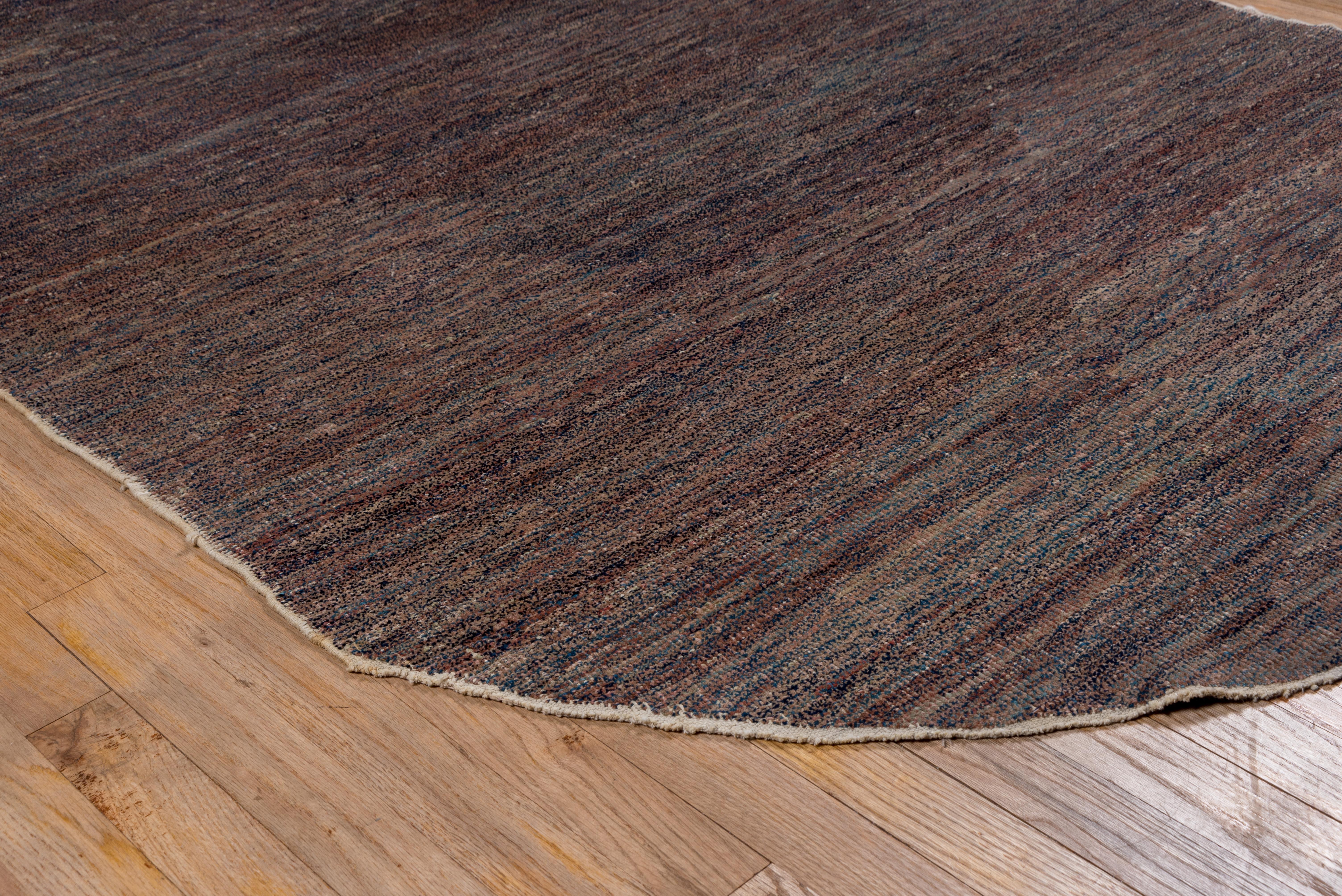 This essentially monochrome, borderless, undecorated elliptical rug has a speckled grey/black pattern constantly varying throughout. The abrash/striation goes end to end and side to side. The condition is fairly good, with a short, brushy pile.
 