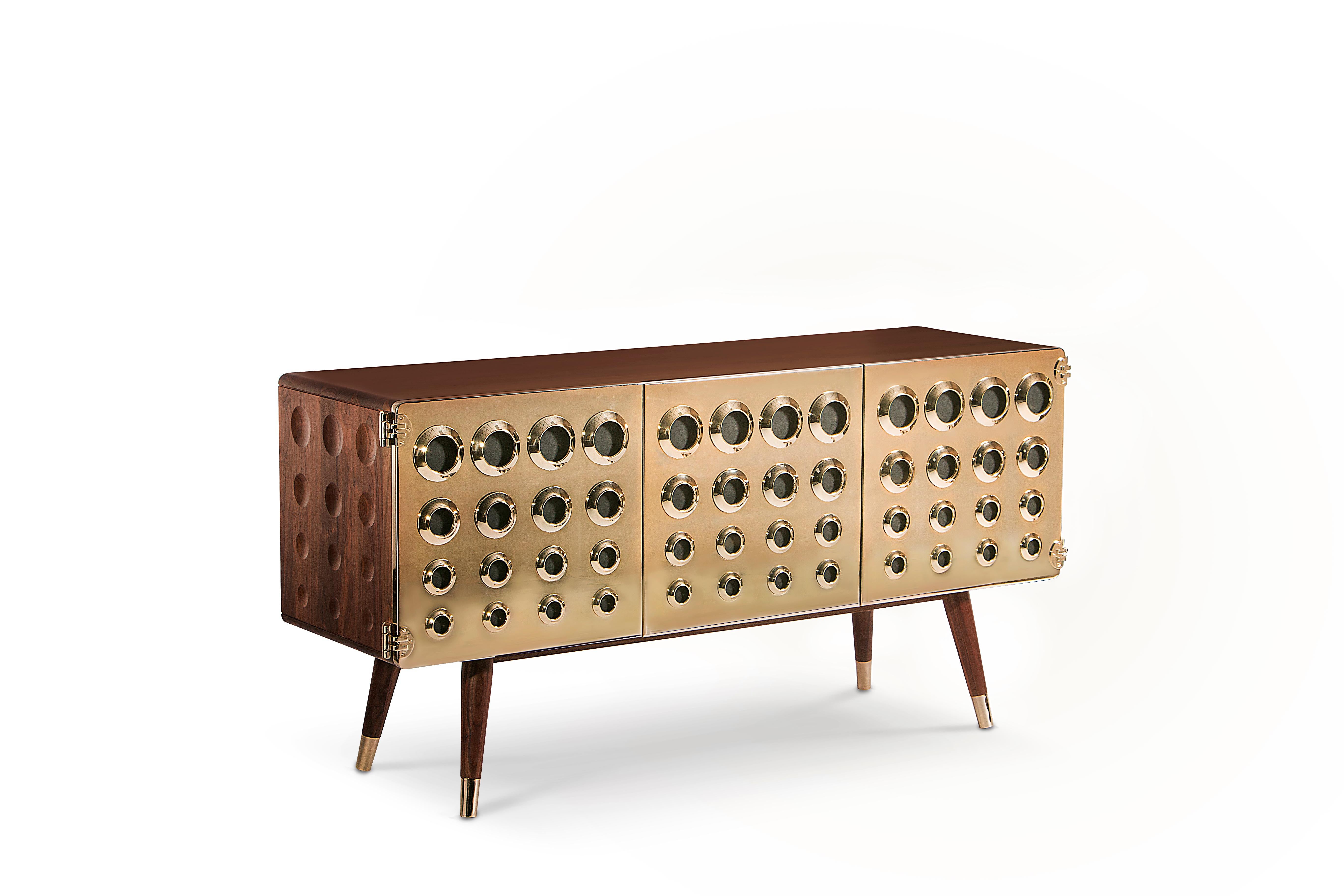 If you are a fan of James Bond's world, you will certainly be dazzled with this golden eye‐catching piece. Our Monocles sideboard is made in solid walnut wood and brass with knurled details. Circles are engraved on the sides and the back in the