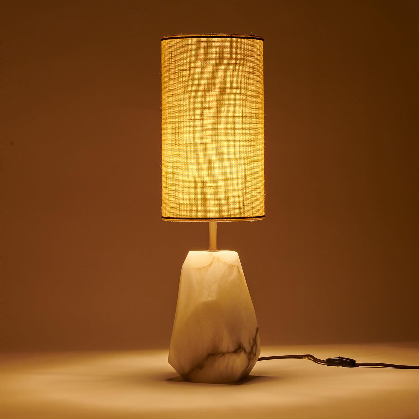 A piece sure to infuse interiors with a striking sculptural allure, this table lamp immediately captures the eye with its base obtained from a faceted row block of prized alabaster. The stone's matte finish ideally combines with the cylindrical