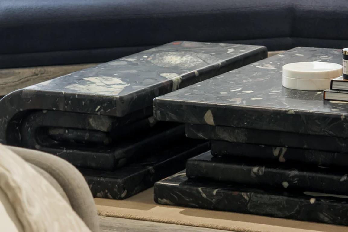 Il tavolino da caffè Monolith di Essentia Home, una straordinaria dichiarazione di eleganza contemporanea, è una miscela perfetta di forme architettoniche e artigianato artistico. Realizzata in pietra nera da terrazzo, la sua presenza audace è