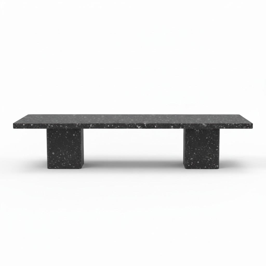 A study in architectural clarity, this dining table is reimagined here in Volcanic Basalt Terrazzo, a deep mineral composite finish that evokes hand-cut basalt and speckled volcanic stone. The elongated monolithic silhouette rests on two block