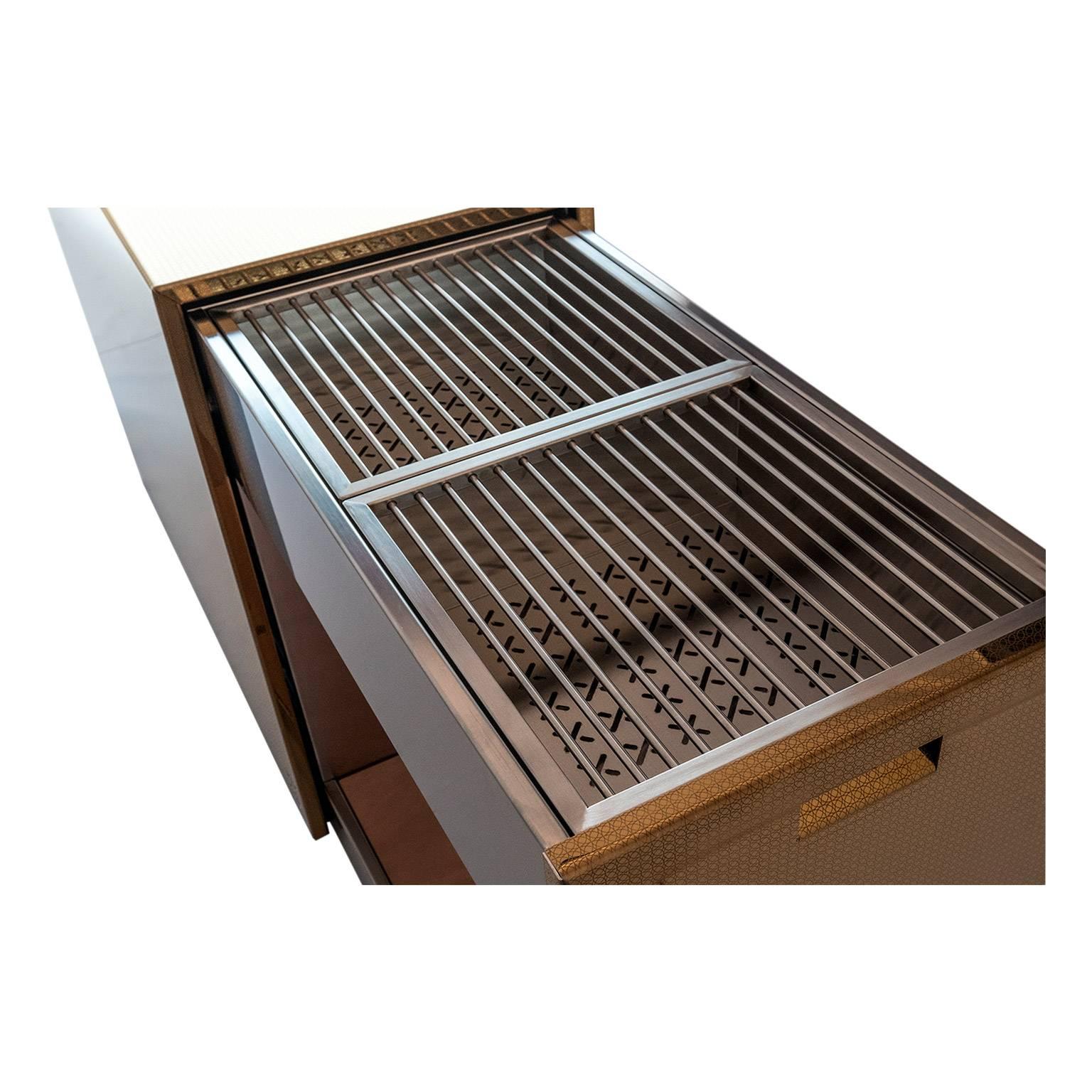 This monolithic charcoal barbecue is elegant and functional with sliding grills and accessories.
The shell protects grills and accessories, it hides and then reveals the extractable soul in stainless steel, that
becomes a comfortable surface for