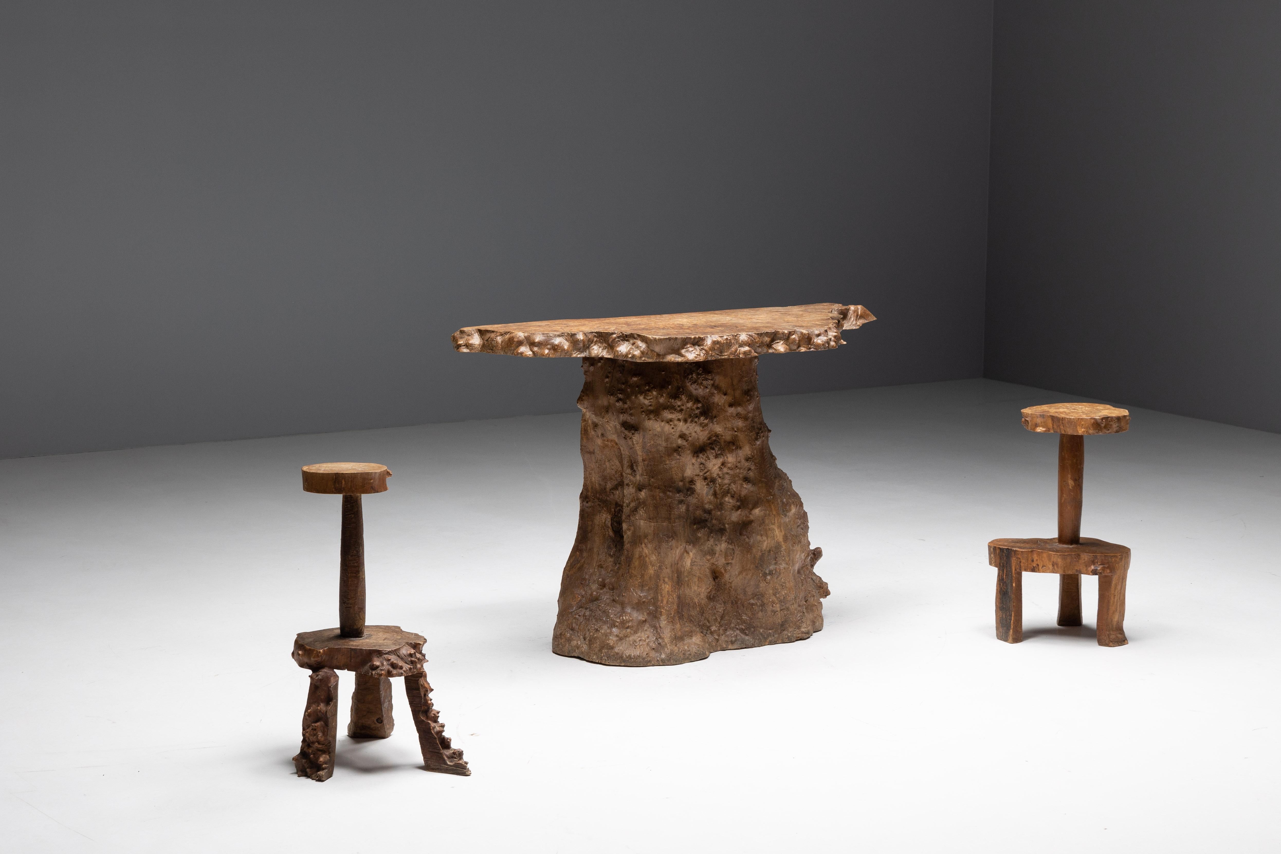 Monxylite bar set, crafted from genuine cedar tree trunks. Each piece celebrates the inherent charm found in organic irregularities. The bar's graceful curves and fluid lines evoke a sense of natural harmony, while the two accompanying tripod stools