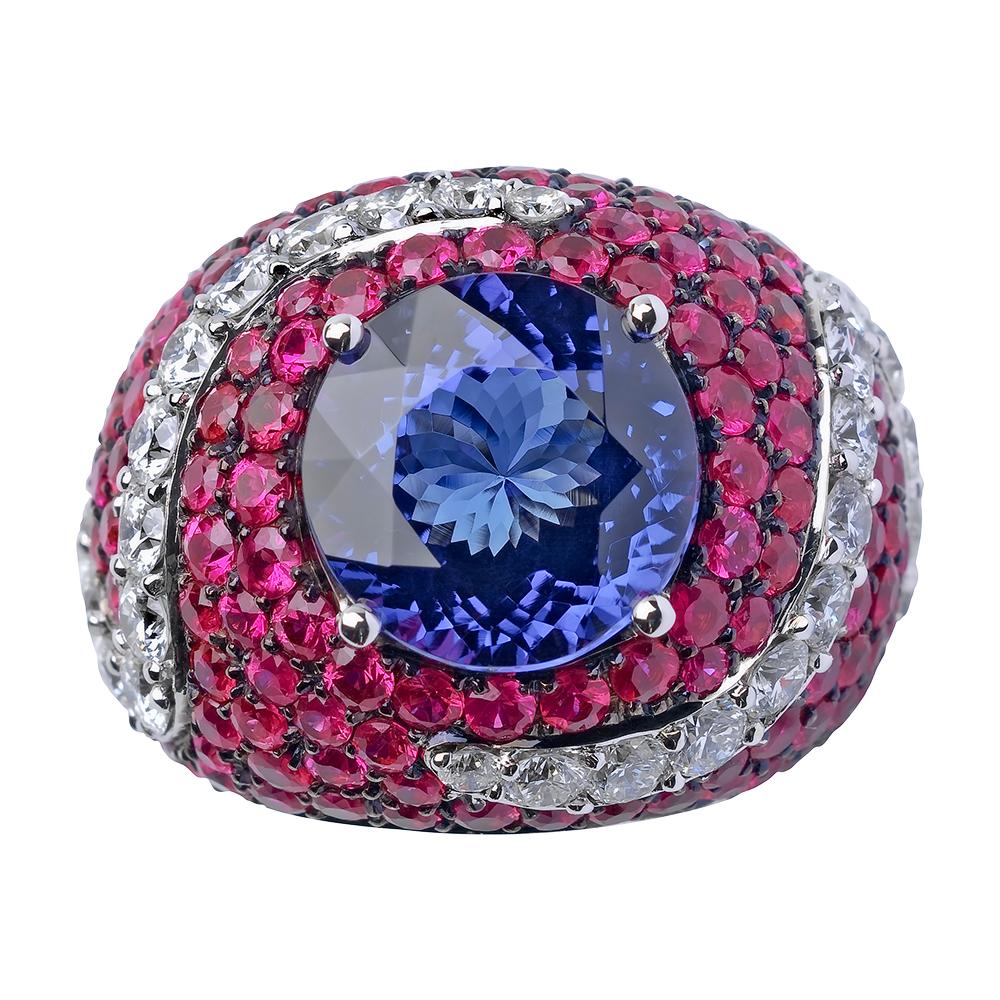 Crafted in 19.2K white gold and set with a 13 mm round tanzanite with a deep saturated blue color along with pink sapphires and diamonds. This large white cocktail gold ring is an unique piece and it has been designed by Monseo's creative director,