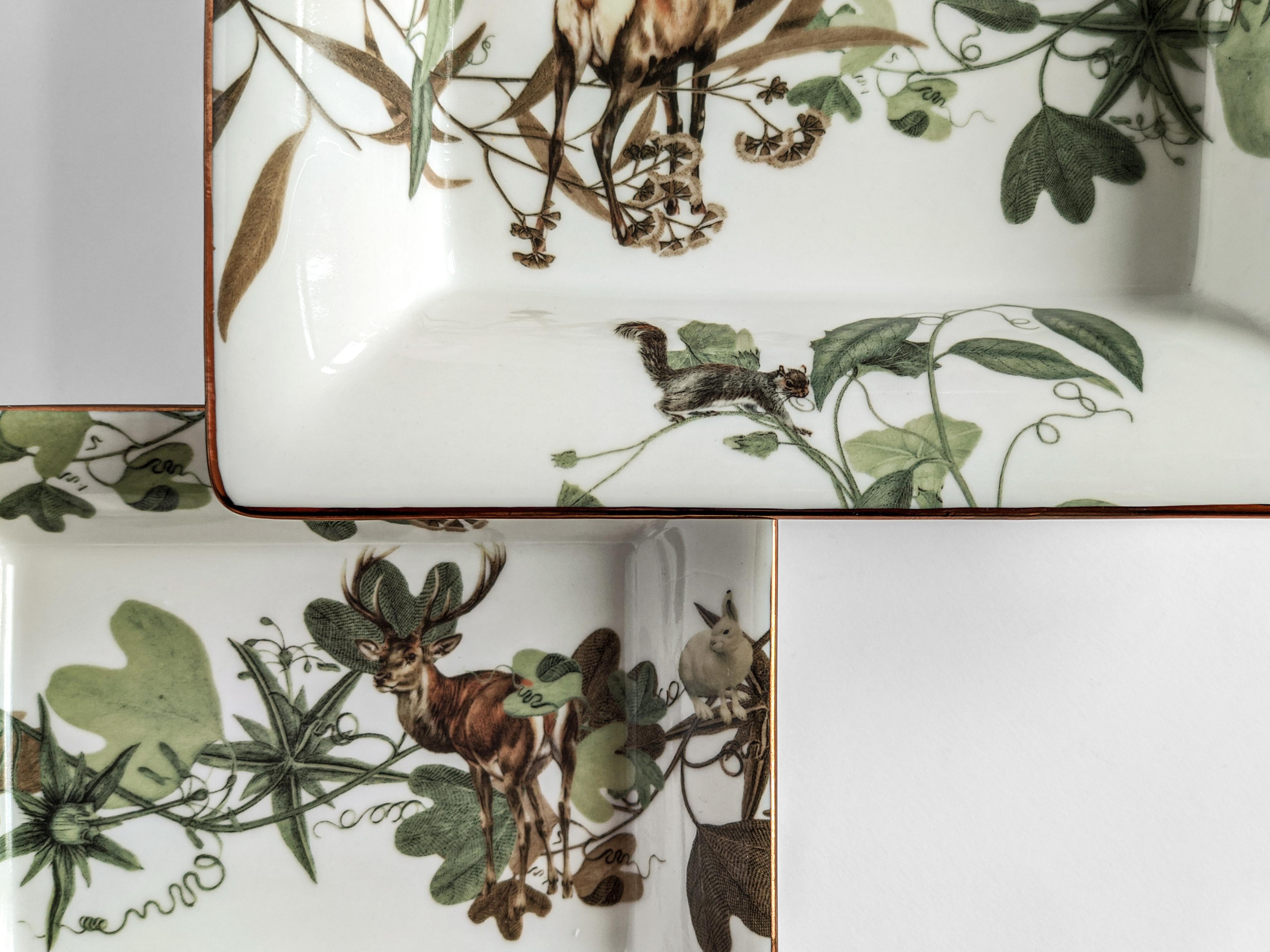 Ein Set aus zwei Porzellan-Taschenentleerern/Aschenbechern mit klassischer Form und einzigartigem Druckdesign. Diese Kollektion ist von Vitos Heimatstadt in Süditalien, Apulien, inspiriert. Diese Artikel sind mit Tieren und Zweigen verziert, die von