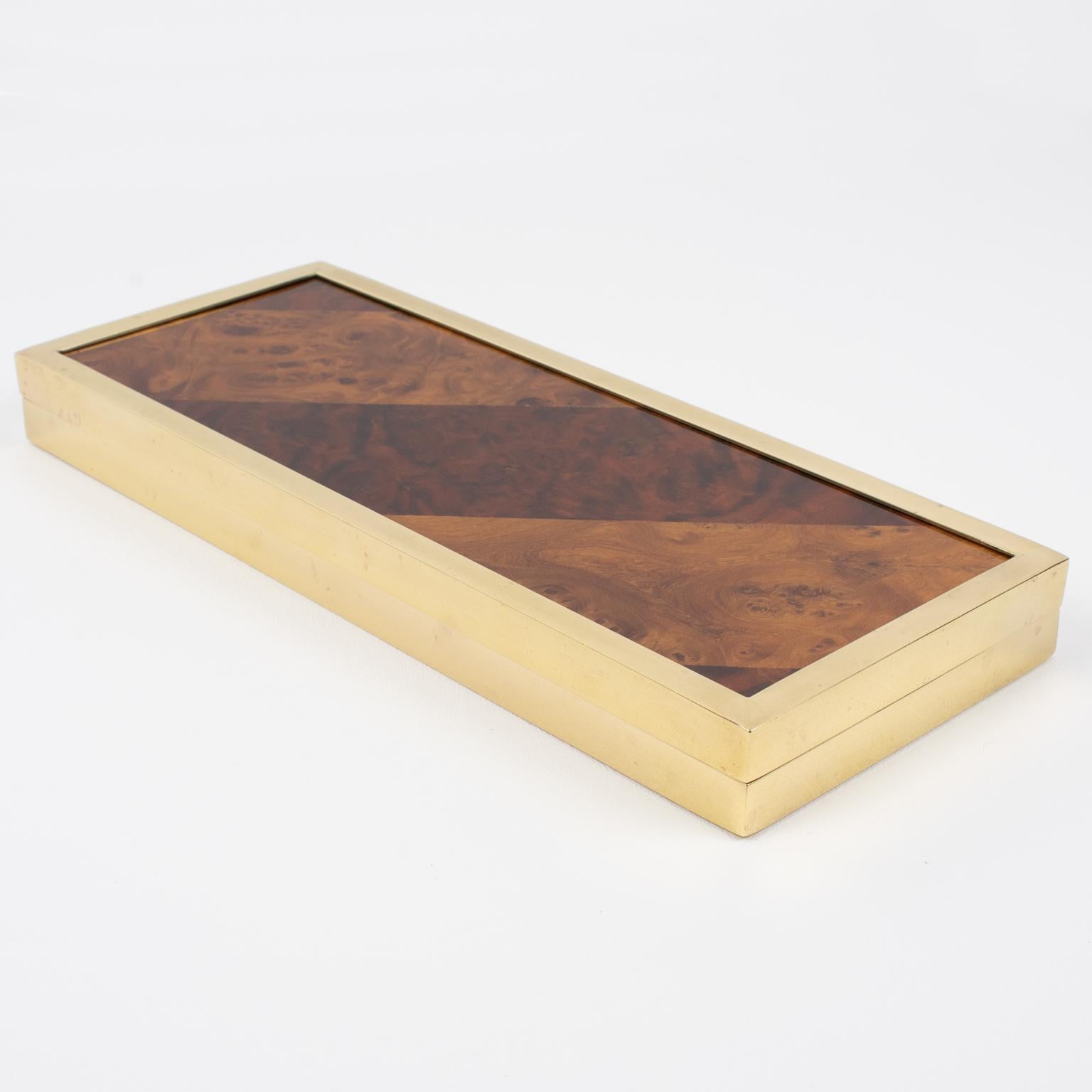 Montagnani Firenze, Italia, diseñó esta lujosa caja decorativa. La pieza se fabricó en Italia hacia el año 1970. Su forma modernista de mediados de siglo presenta una forma plana rectangular alargada, con chapa de marquetería geométrica de madera