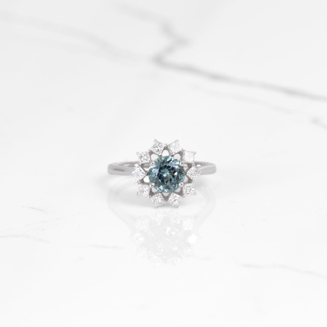 This gorgeous ring is nothing but unique! The center is a beautiful Montana sapphire that is 1.45 carats, and it truly glistens! Surrounding the sapphire is a stunning princess cut diamond halo that is a total of .57 carats. All set in 14k white