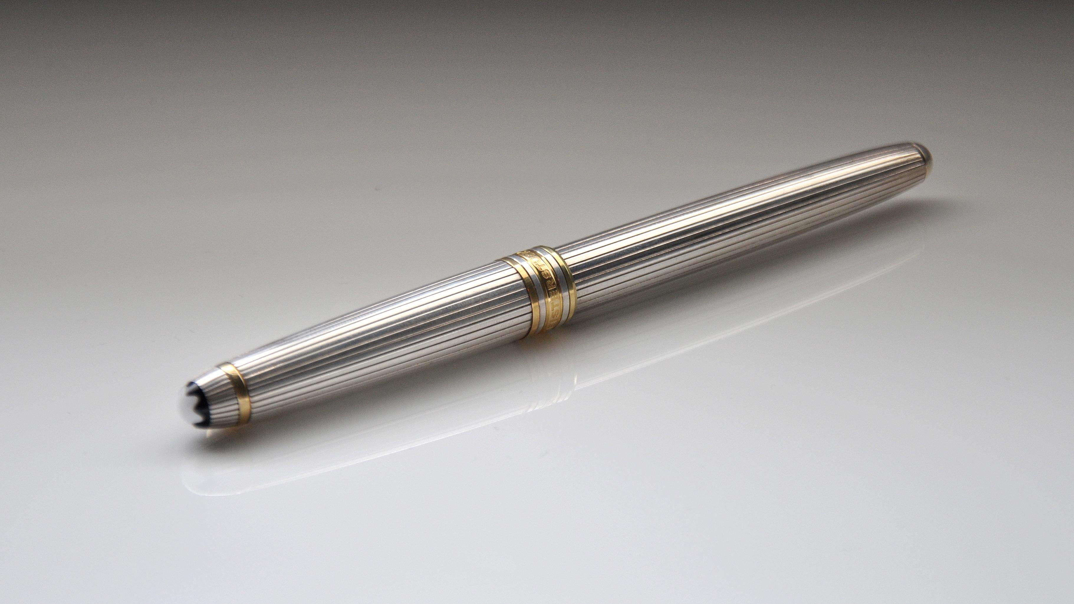 A vintage 925 silver Montblanc Meisterstück 164 rollerball pen, in the Godron pattern. The pen's barrel and cap are made of 925 sterling silver and feature a fluted or pinstripe pattern. The 925 silver rings, clip and tip are gold-plated. The cap is