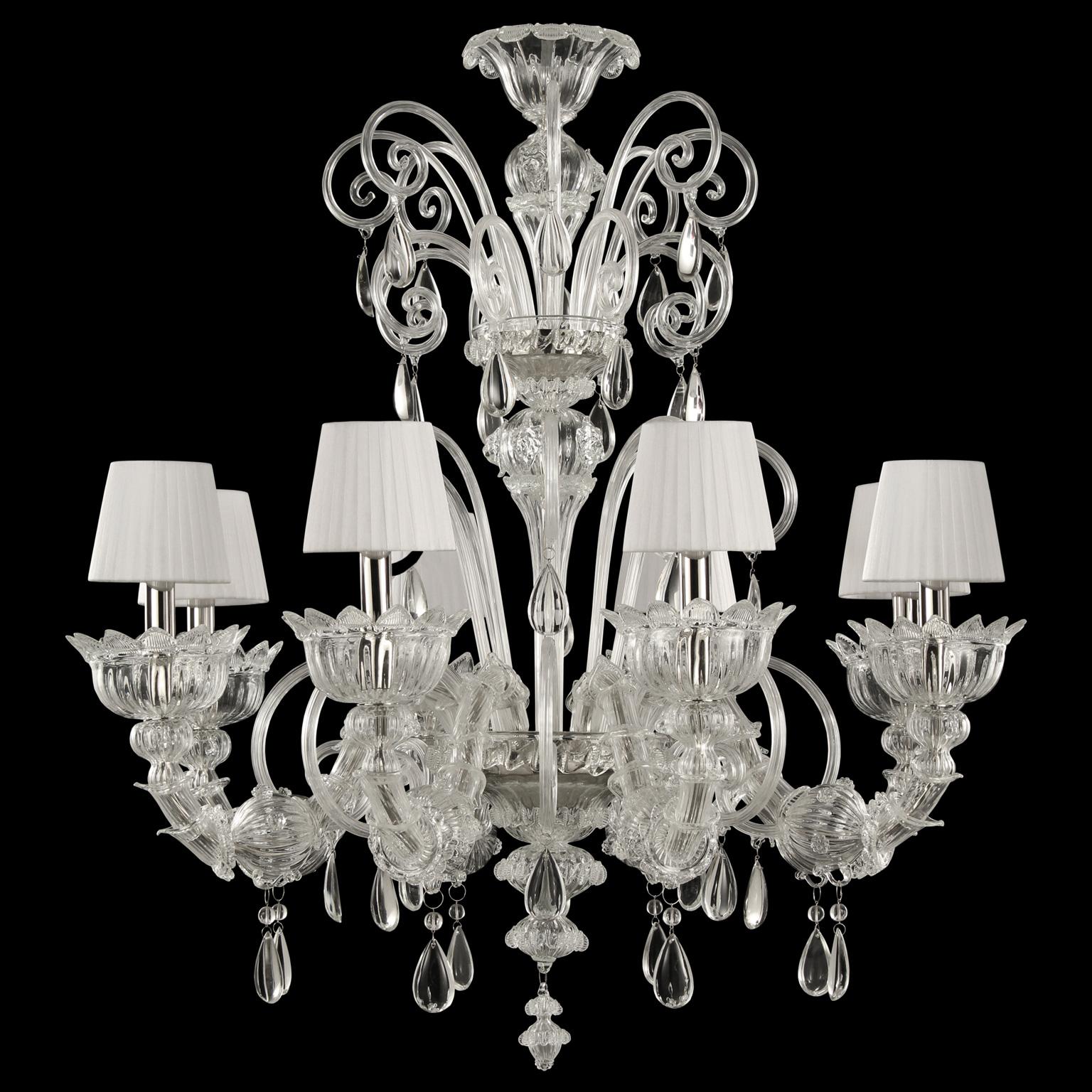 Montecristo chandelier 8 arms, artistic clear glass, white organza lampshades by Multiforme.
Montecristo collection is created with the typical elements of Venetian glass chandeliers. From the central column, decorated with “morrise” and roses,