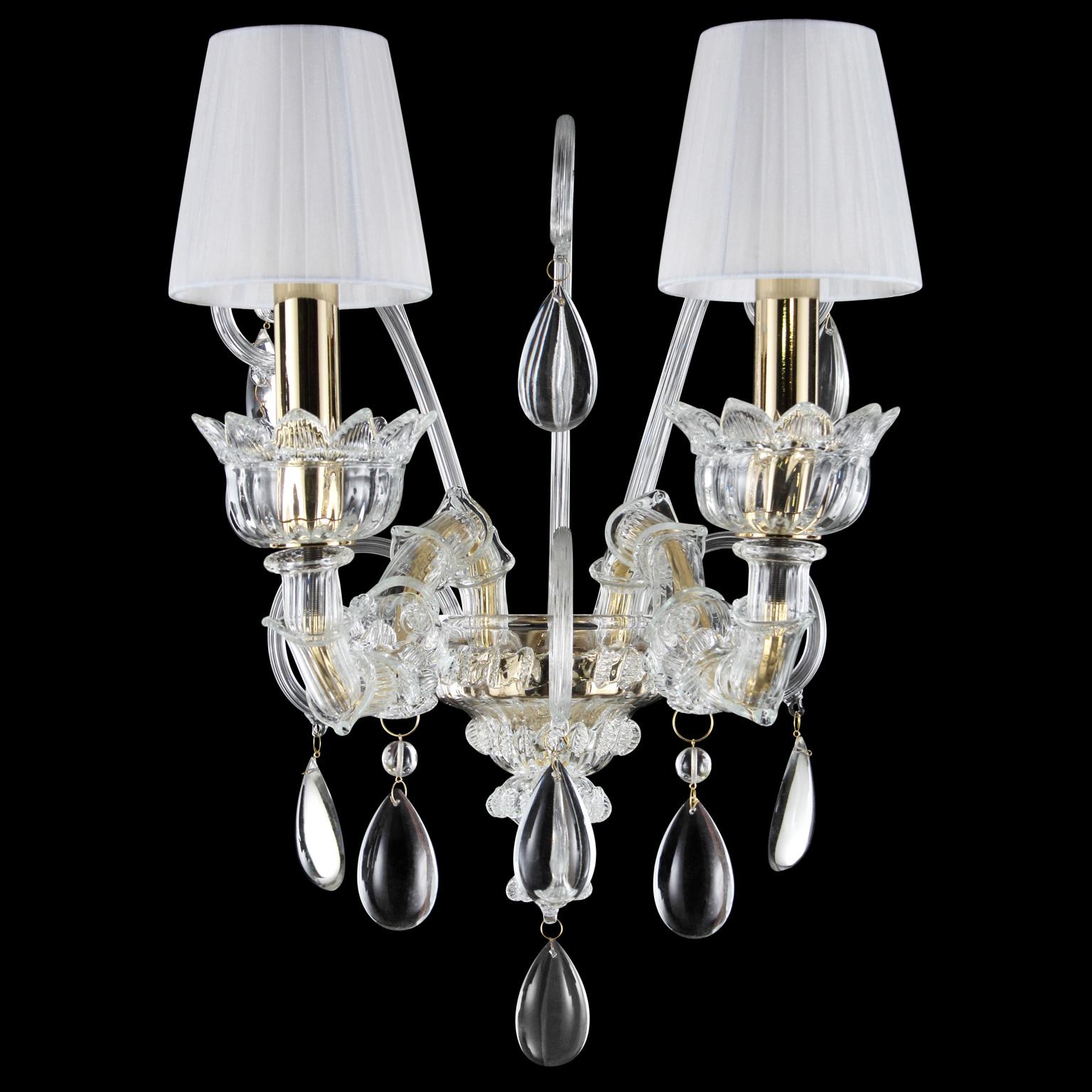 Montecristo wall, 2 lights, artistic glass, white organza lampshades by Multiforme.
Montecristo collection is created with the typical elements of Venetian glass chandeliers. From the central column, decorated with “morrise” and roses, depart the