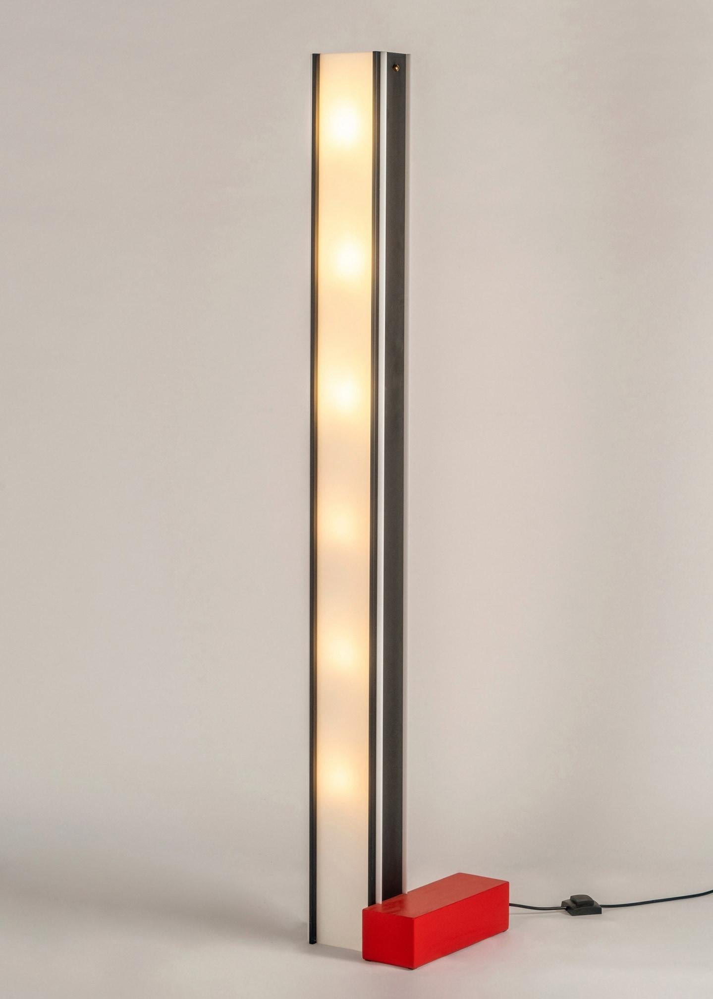 Floor lamp in black painted metal and plexiglass. The red metal base recalls the brand's iconic colors.