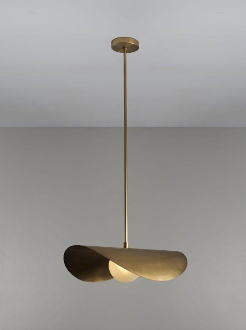 The Montera Pendant features an undulating, biomorphic form atop a single-blown satin glass globe. This creates a flattering indirect overhead light—perfect for grouping over a kitchen island or bar. Fabricated in brass and shown in our