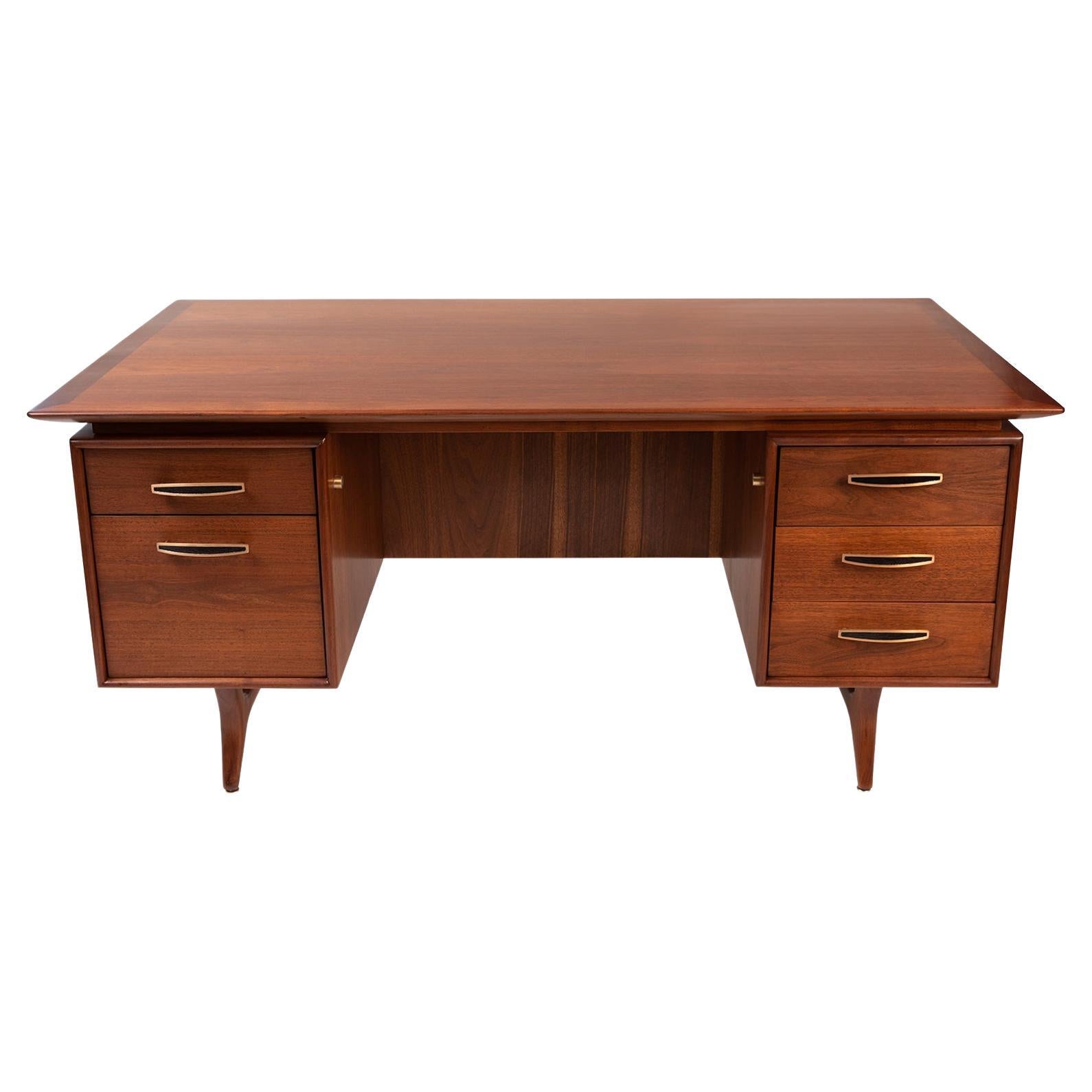 Monteverdi-Young walnut and brass desk circa late 1950s. This example has fabulous solid walnut legs, polished brass handles and lots of storage and work space. It has been newly and masterfully refinished.