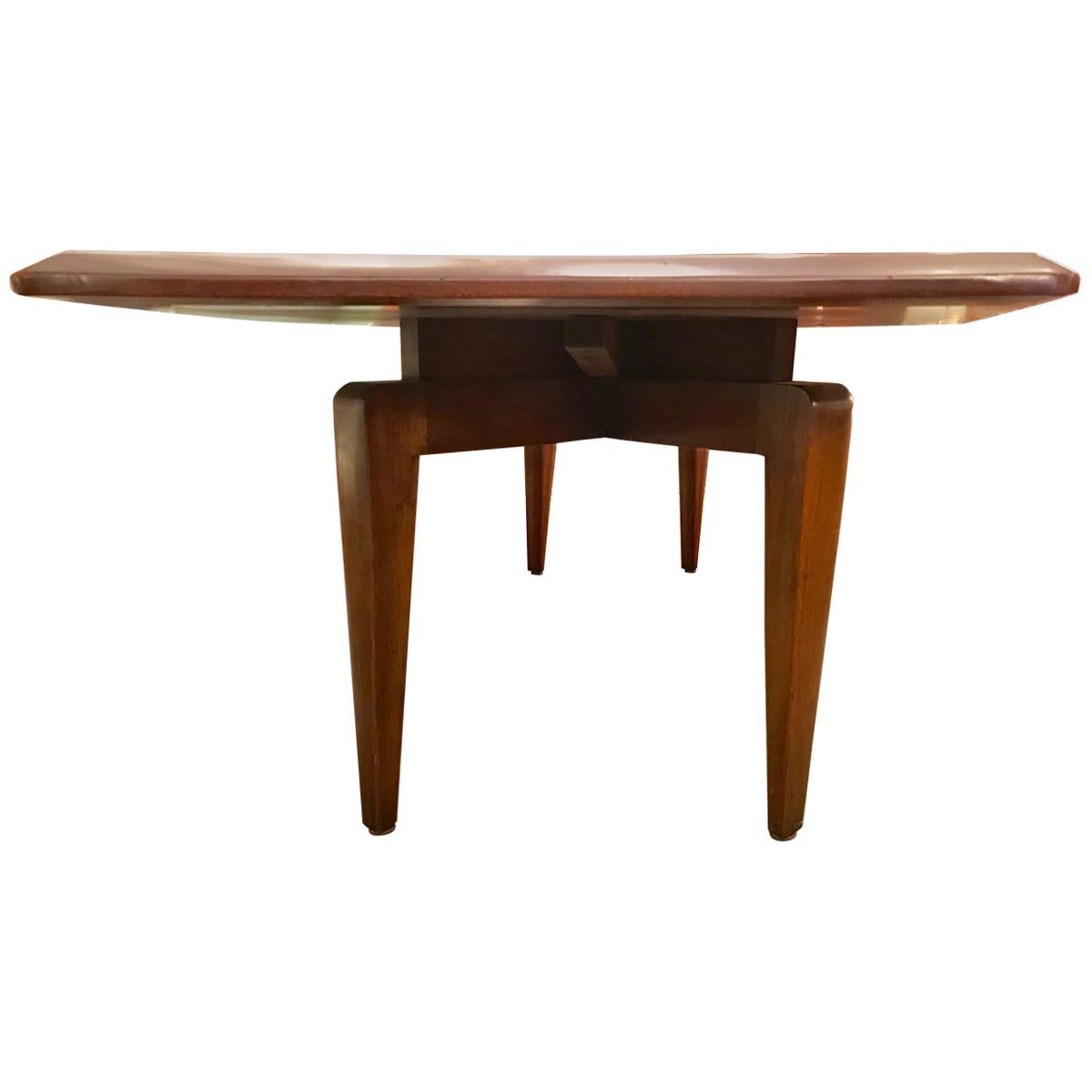Sleek and sophisticated, this shapely Mid-Century Modern dining table is composed of walnut and features a geometric top with a bevelled edge and ebonized detailing. Stamped for ensured authenticity, this eye-catching dining table boasts rounded and