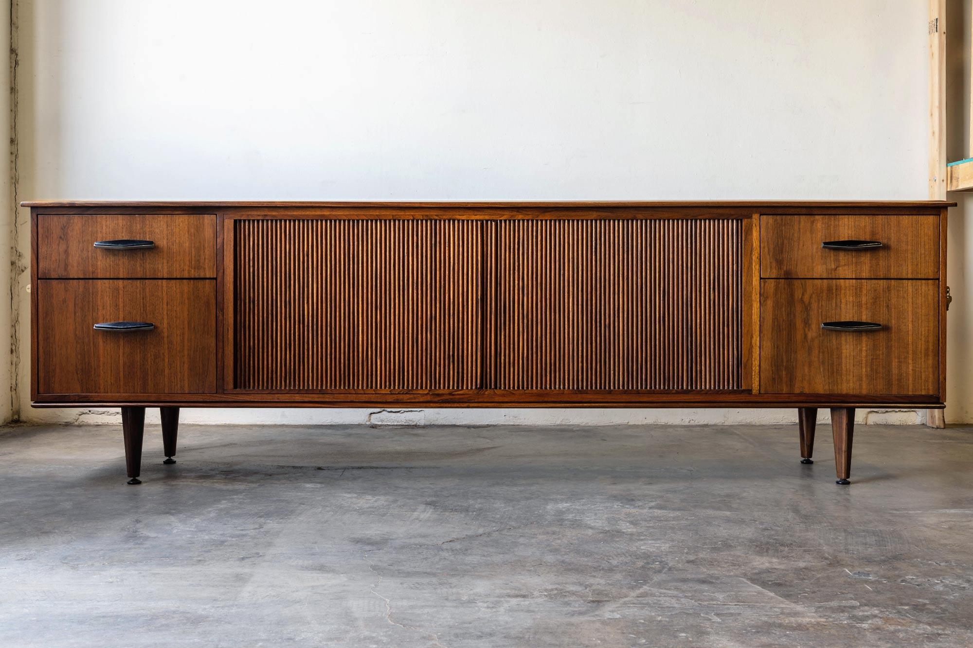 Add a touch of vintage charm to your home decor with this fully refinished tambour walnut sideboard by Maurice Bailey for Monteverdi Young. With its elegant design and rich walnut wood grain, this piece is a true showstopper. The convenient tambour