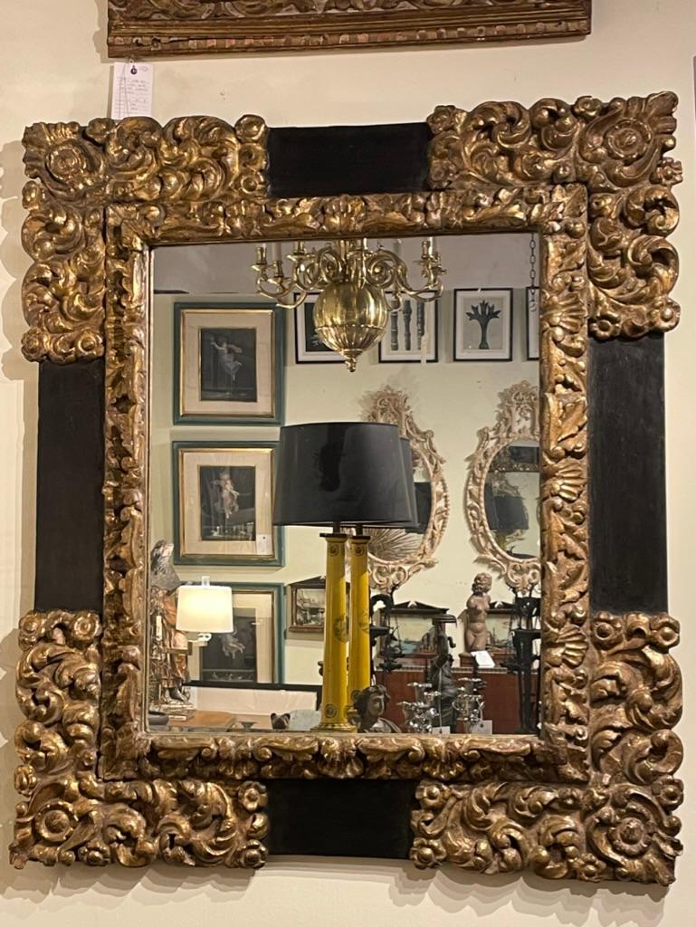 Spanish Baroque period monumental carved and ebonized gilt wood frame holding a mirror. Carved in the early 17th century, the frame is in great antique condition with age-appropriate wear and use. This stunning frame will make a room.
 
The frame