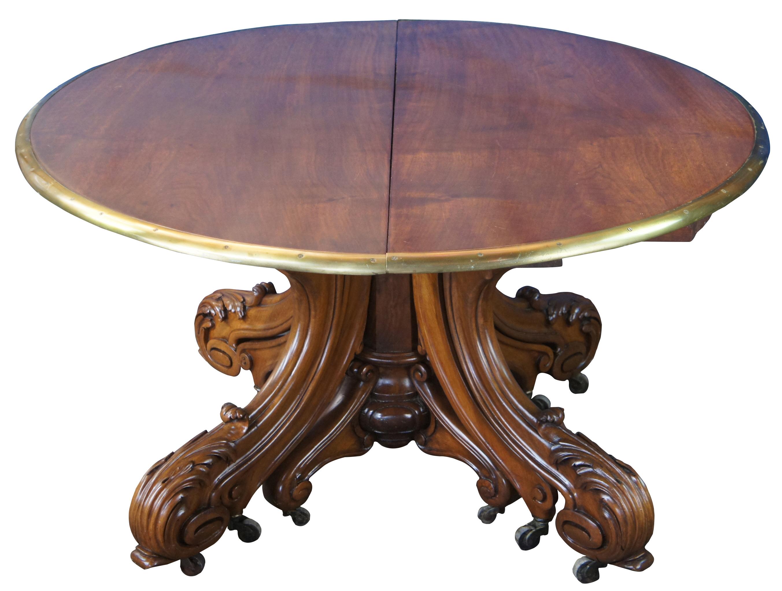 A fine and impressive round extendable museum quality conference or dining table, circa 1850s. Made from solid walnut with 3 stage extendable brass banded top Features acanthus scrolled and carved legs as well as casters for ease of opening. The 8