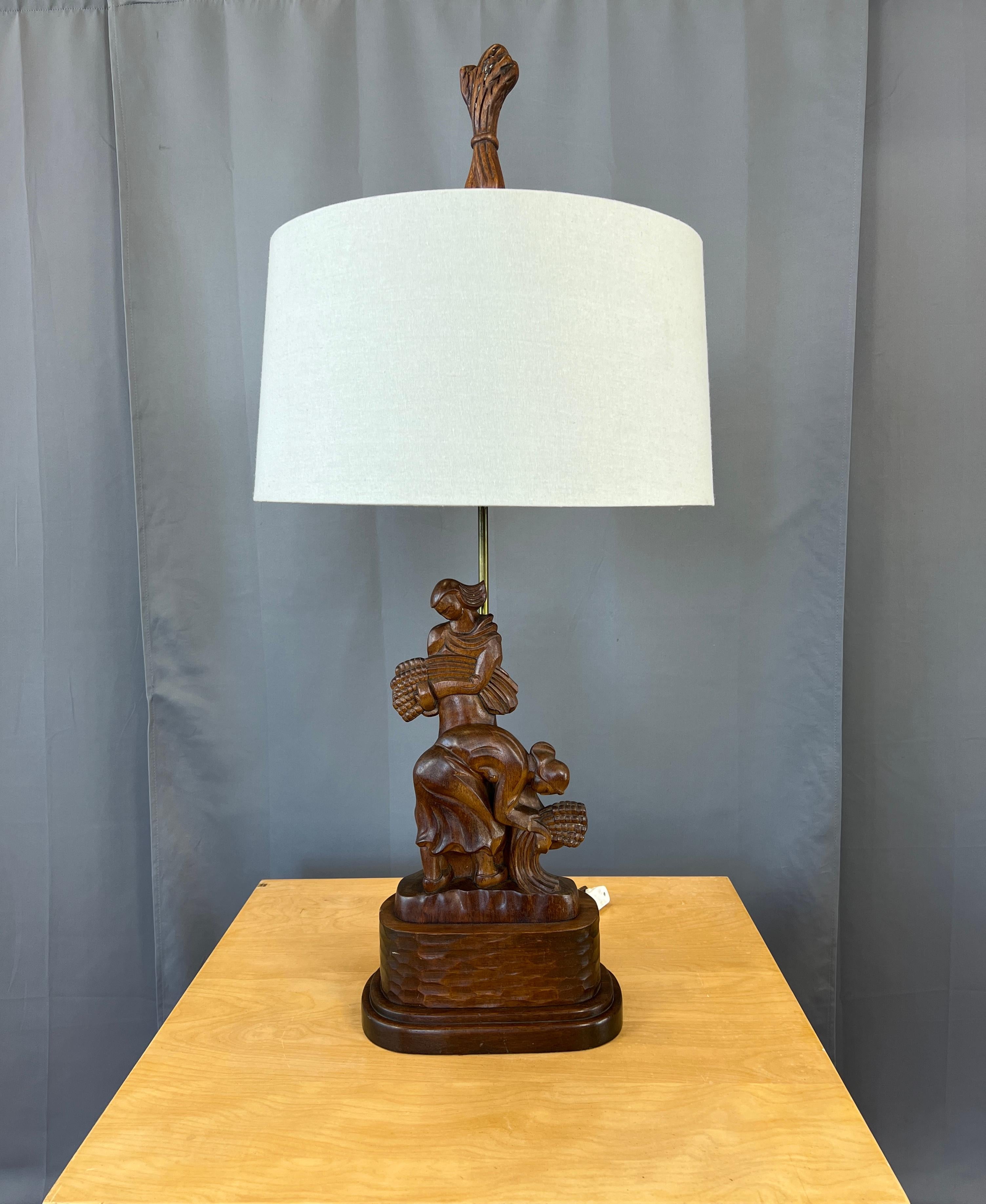 Hier wird eine monumentale geschnitzte Mahagoni-Tischlampe aus den 1940er Jahren angeboten, deren Design von Frauen beim Ernten von Weizen zeigt.
Auf der Rückseite ist der Herstellername Heifetz eingraviert.

Die unten angegebenen Maße beziehen