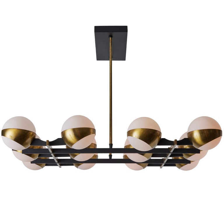 Monumental 1950s 12-Globe Glass & Metal Chandelier for Stilnovo. Executed in 12 opaline glass globes, brass and black enameled metal. An iconic Italian light sculpture of impressive scale and incomparable refinement. Sourced from an estate in Forest