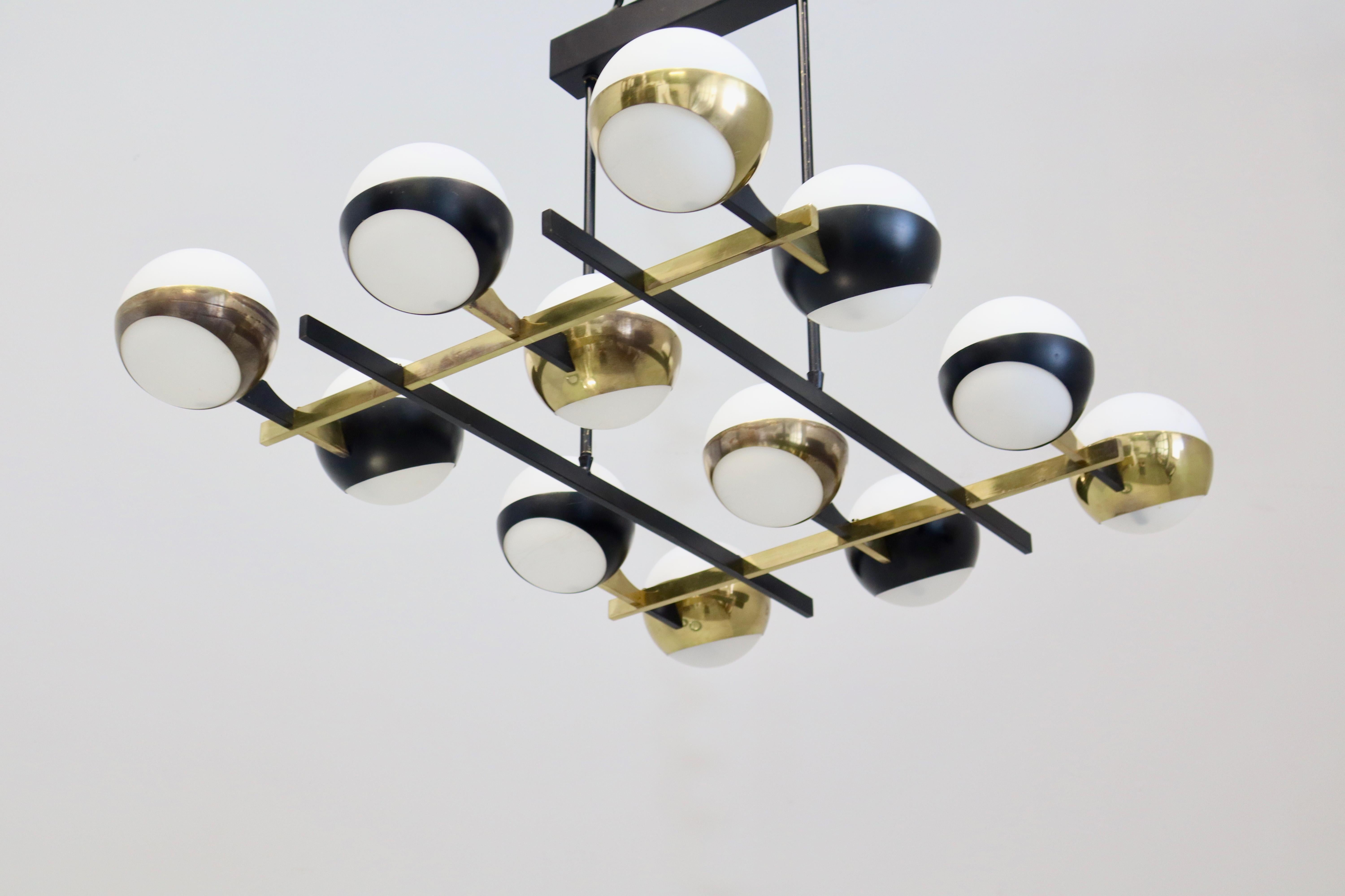 Monumental lustre en verre et métal à 12 globes des années 1950 pour Stilnovo.
 
Exécuté en 12 globes de verre opalin, laiton et métal émaillé noir. Une sculpture lumineuse italienne emblématique d'une ampleur impressionnante et d'un raffinement