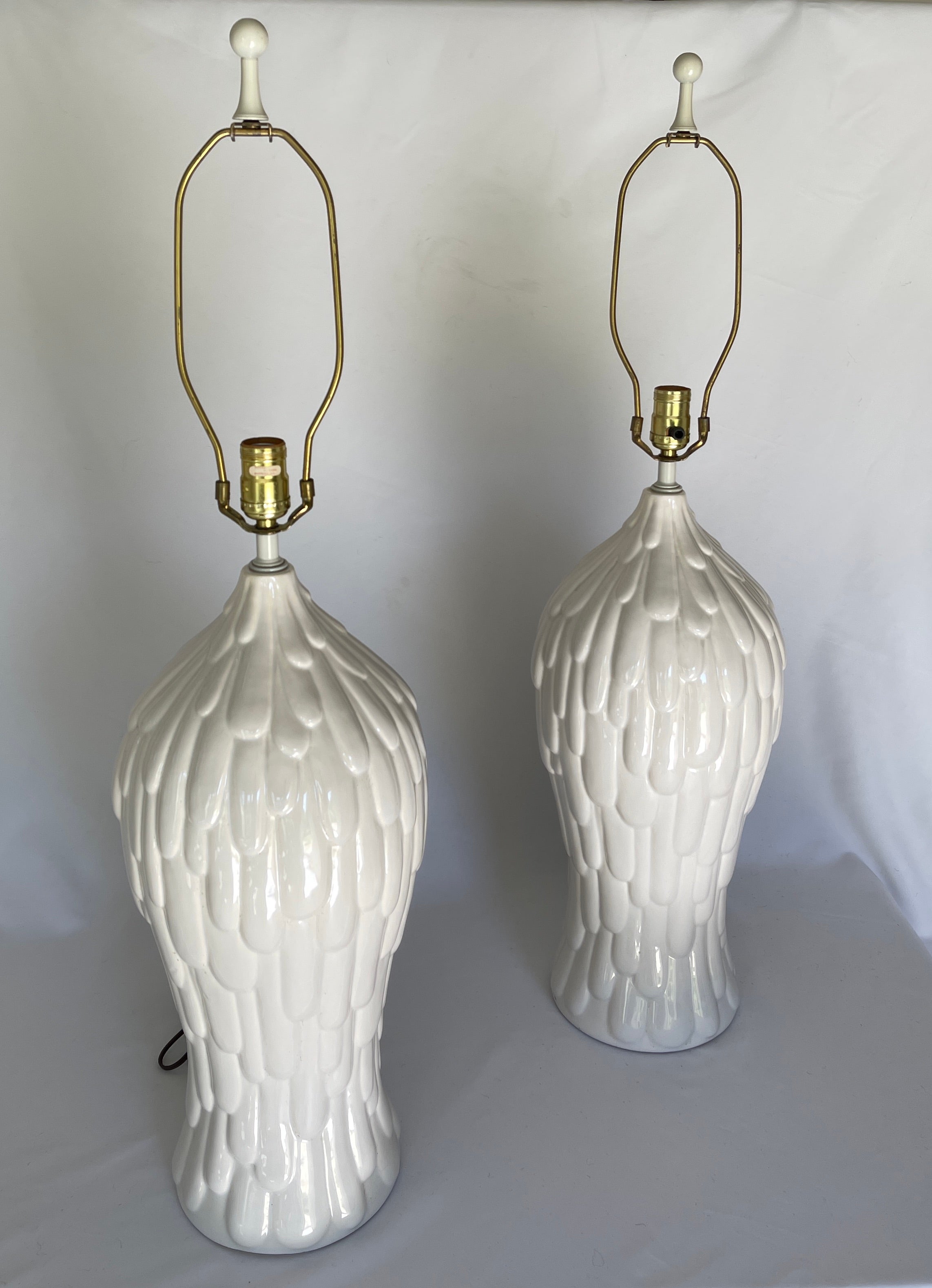 Monumental 1980's pair of glazed white pottery lamps, with original white enamelled finials. Signed Royal Haeger, with paper label on socket.

Lamps measure:
 35