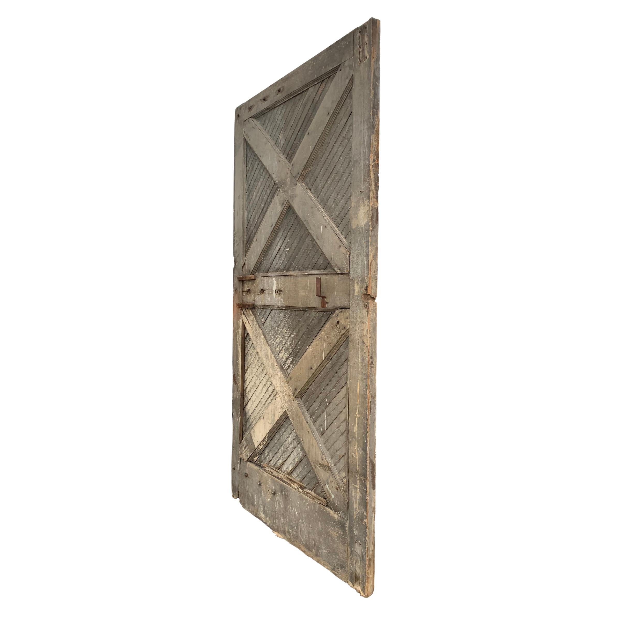 A monumental 19th century American barn door with two large X supports across the front, with diagonal painted beadboard with an alligator finish splashed with white paint, and large iron hardware that is original to the door.  This would make the